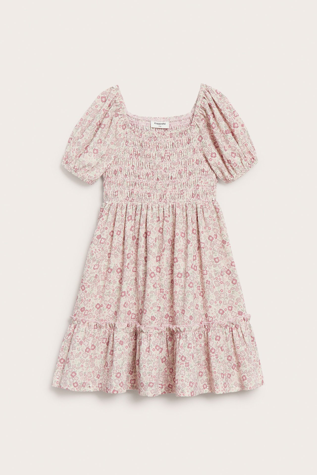 Edestä kuvattu lasten vaaleanpunainen kukkakuvioinen kreppijersey-mekko pöyheillä hihoilla ja smokkirypytyksellä.