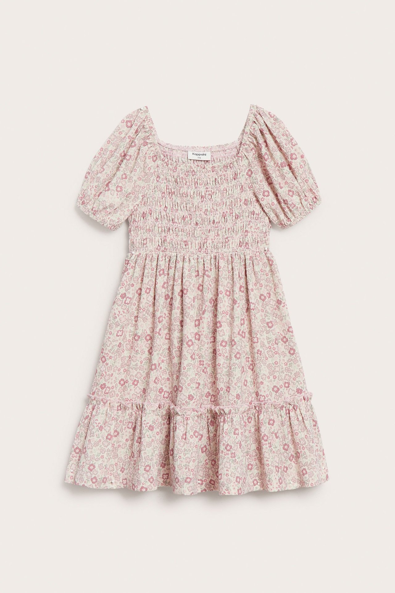 Frontvisning av en lyserosa blomstret barnekjole i krøllete jersey med puffermer og smocket overdel.
