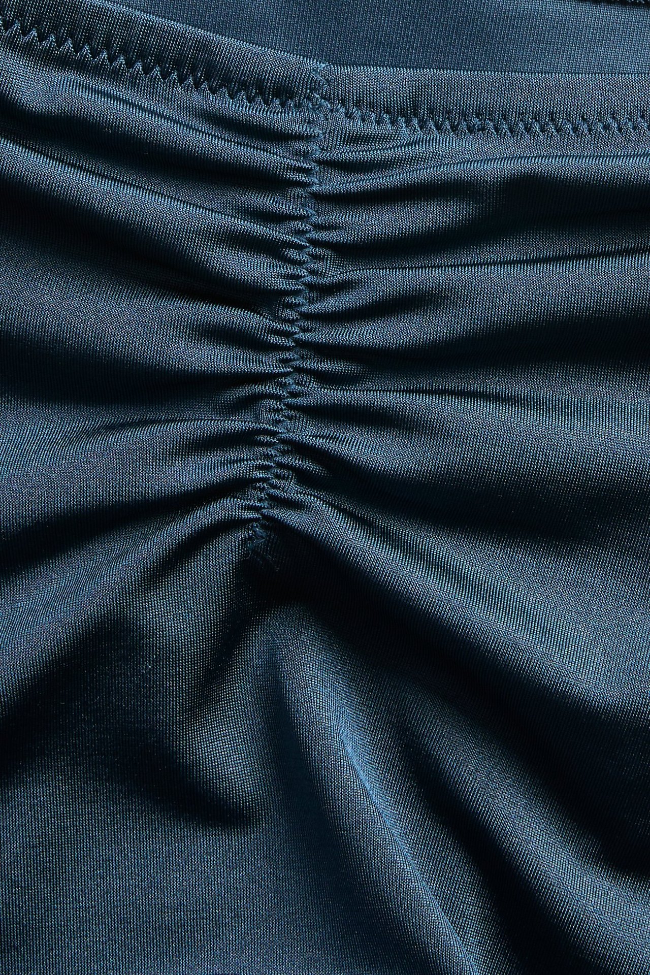 Nærbilde av en mørkeblå ensfarget bikinitruse med rynket detalj.