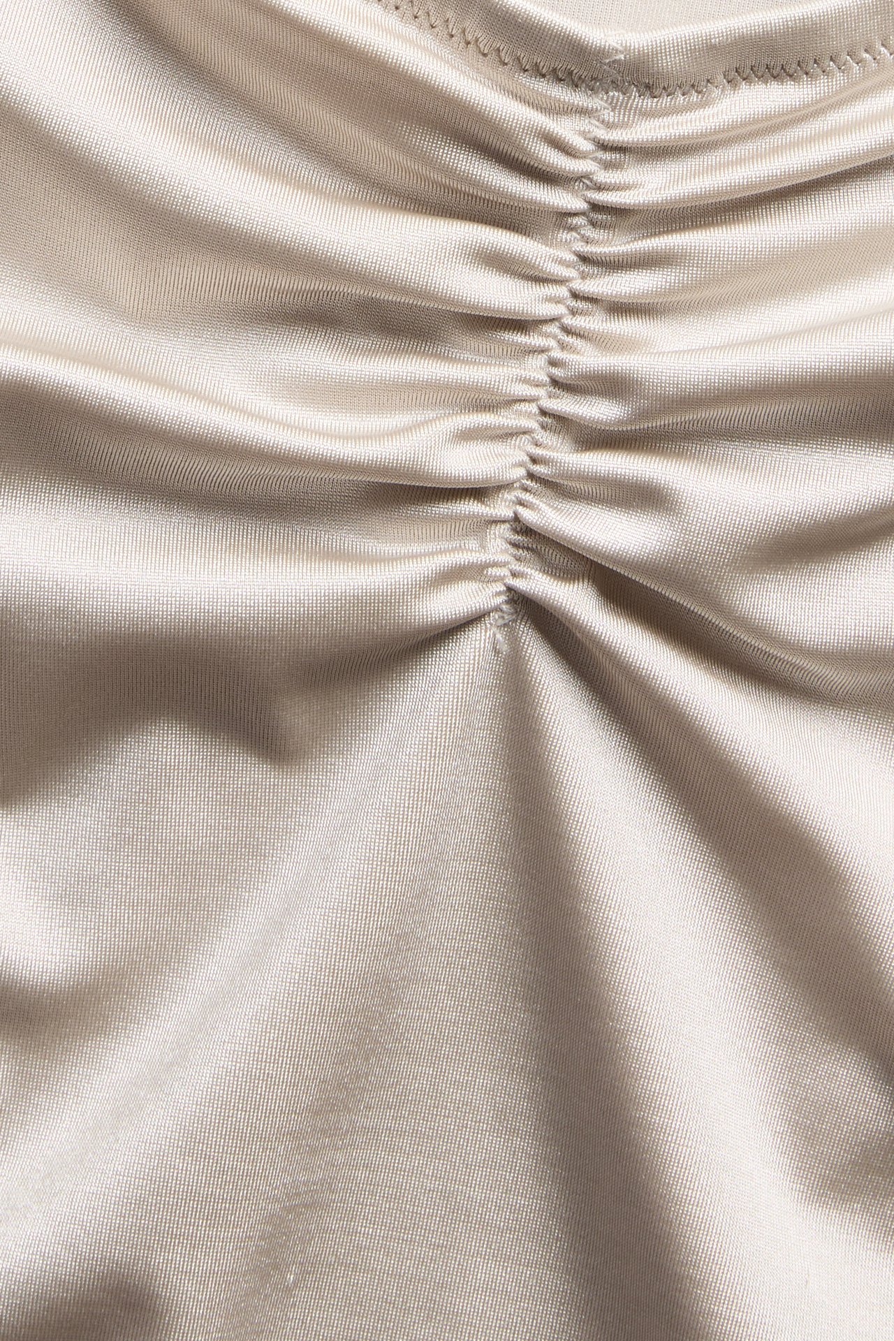 Nærbilde av beige ensfarget bikinibunnstoff med rynket detalj.