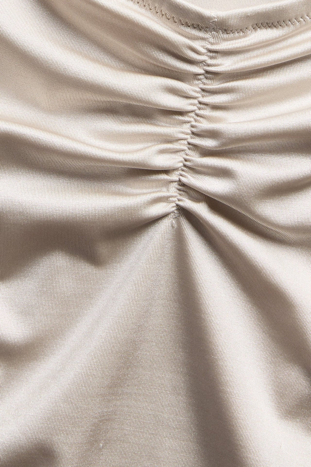Nærbilde av beige ensfarget bikinibunnstoff med rynket detalj.