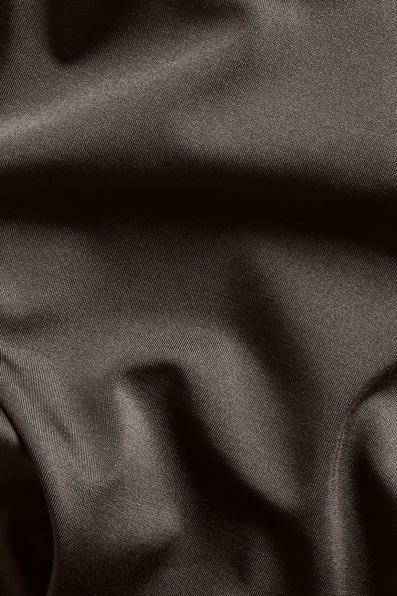 Nærbilde av brunt ensfarget stoff for bikinitruse, med lett tekstur og folder.