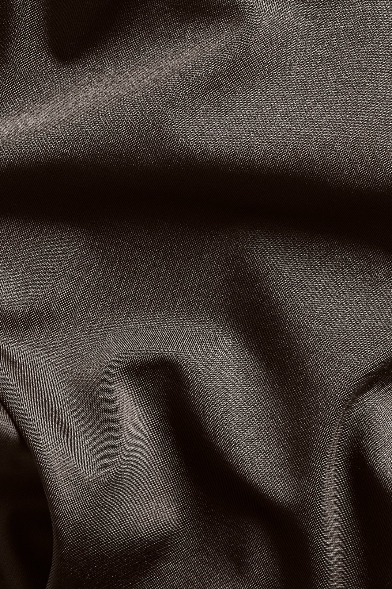 Nærbilde av brunt ensfarget stoff for bikinitruse, med lett tekstur og folder.