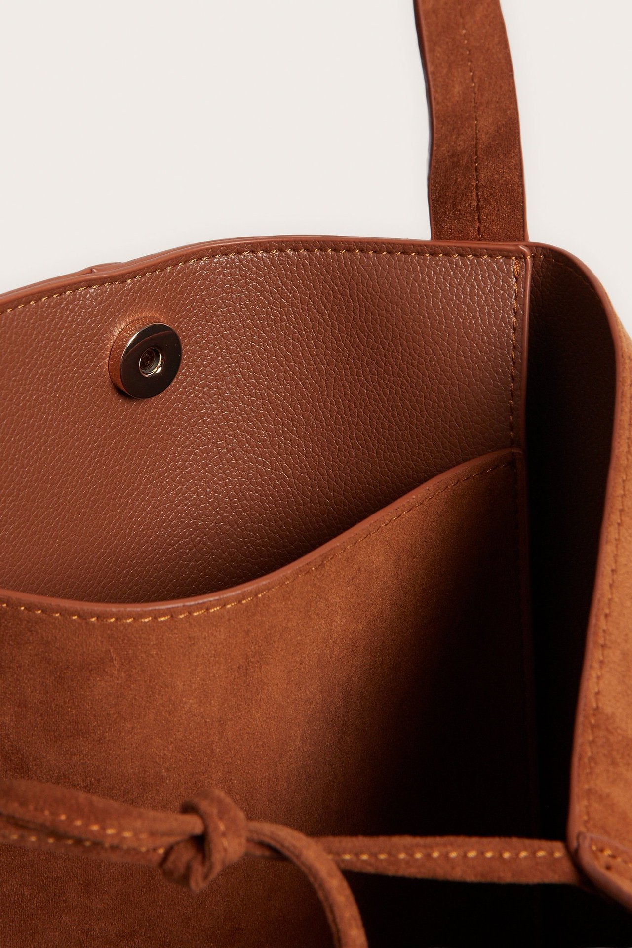 Lähikuva ruskeasta mokkajäljitelmälaukusta, jossa on magneettikiinnitys ja sisätasku.