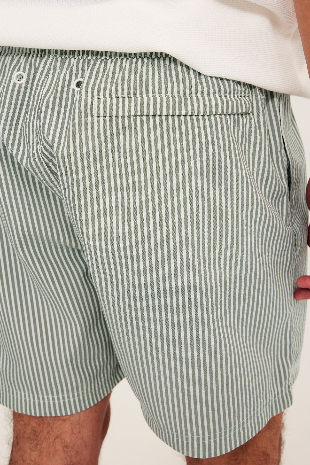 Zbliżenie: mężczyzna w ciemnozielonych prążkowanych kąpielówkach seersucker, z elastycznym pasem i tylną kieszenią.