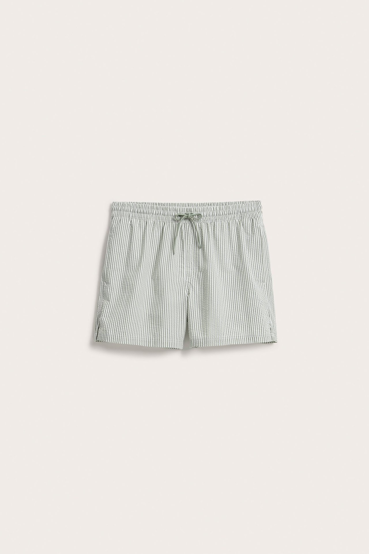 Widok z przodu zielonych w paski szortów kąpielowych z seersuckeru z elastycznym sznurkiem w pasie.