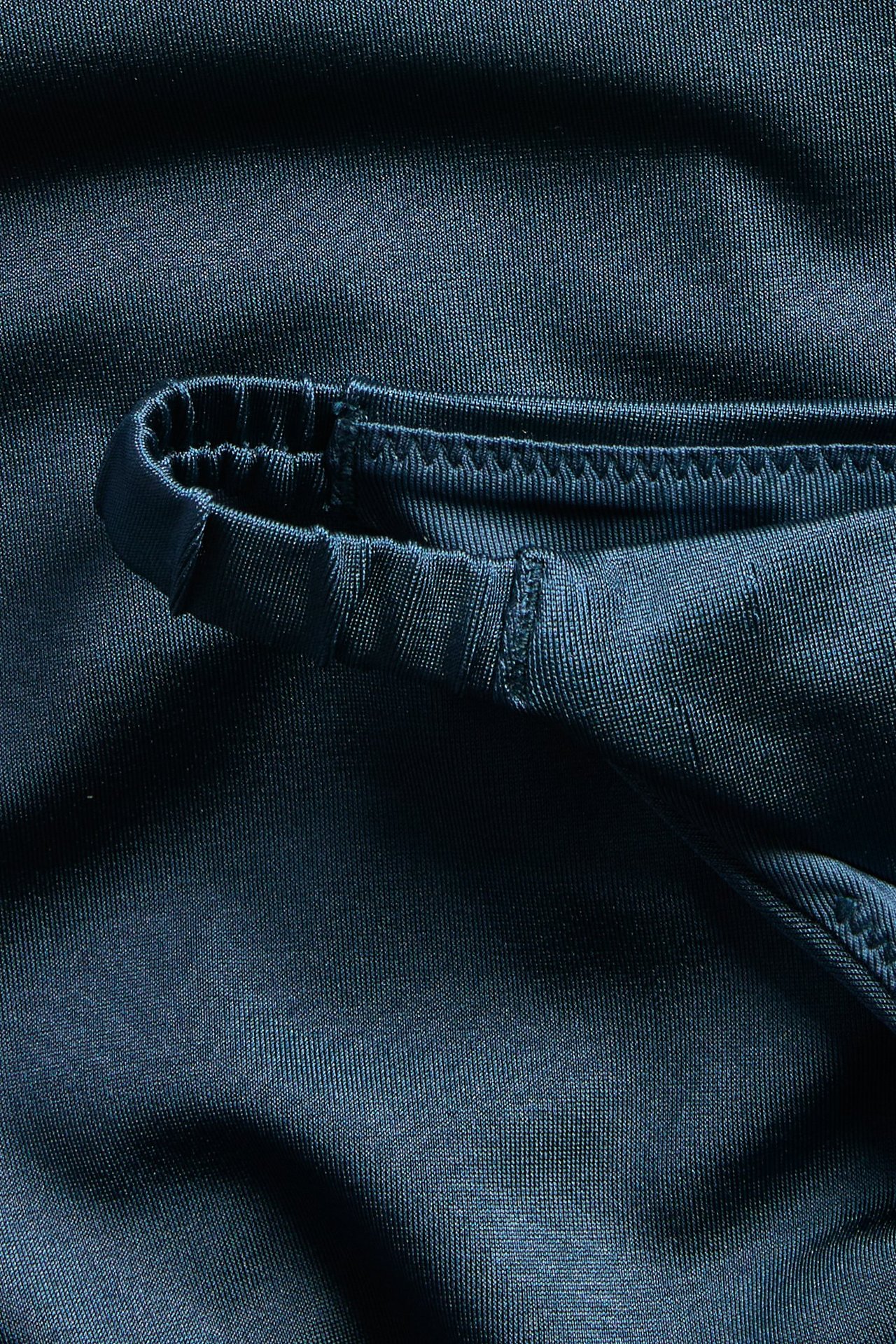 Lähikuva tummansinisestä yksivärisestä brazilian-bikinialaosasta, jossa on joustava reuna.