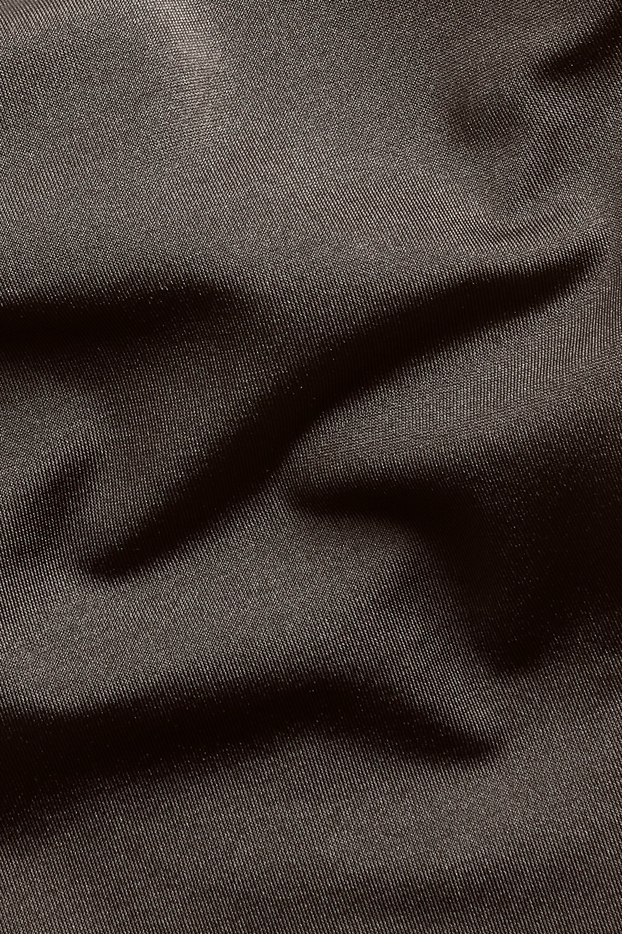 Lähikuva ruskeasta, yksivärisestä bikinikankaasta, jossa on hienovaraista tekstuuria ja taitoksia.