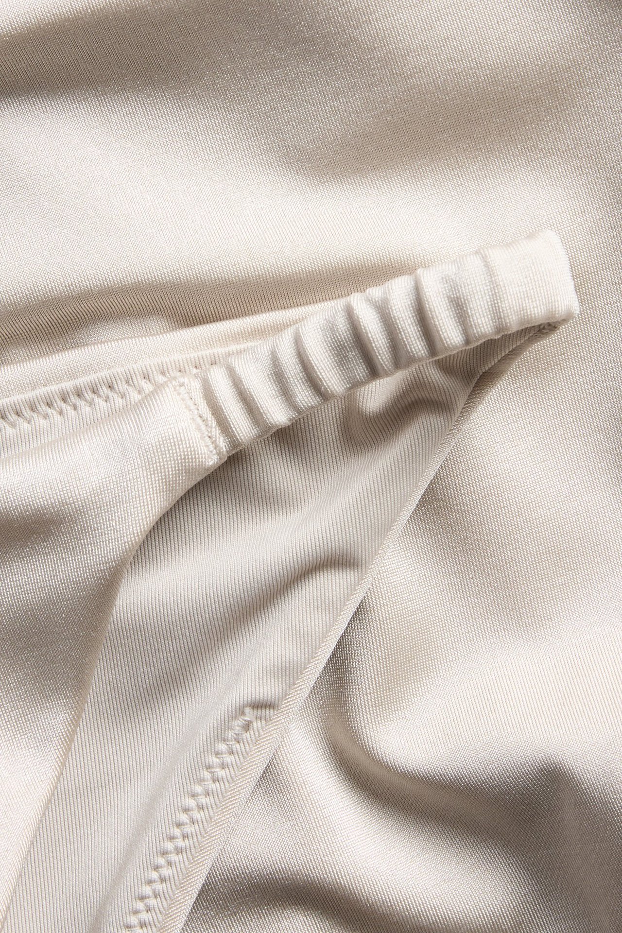 Lähikuva beigestä brazilian-bikinihoususta, näyttää sileän kankaan ja joustavan vyötärön.