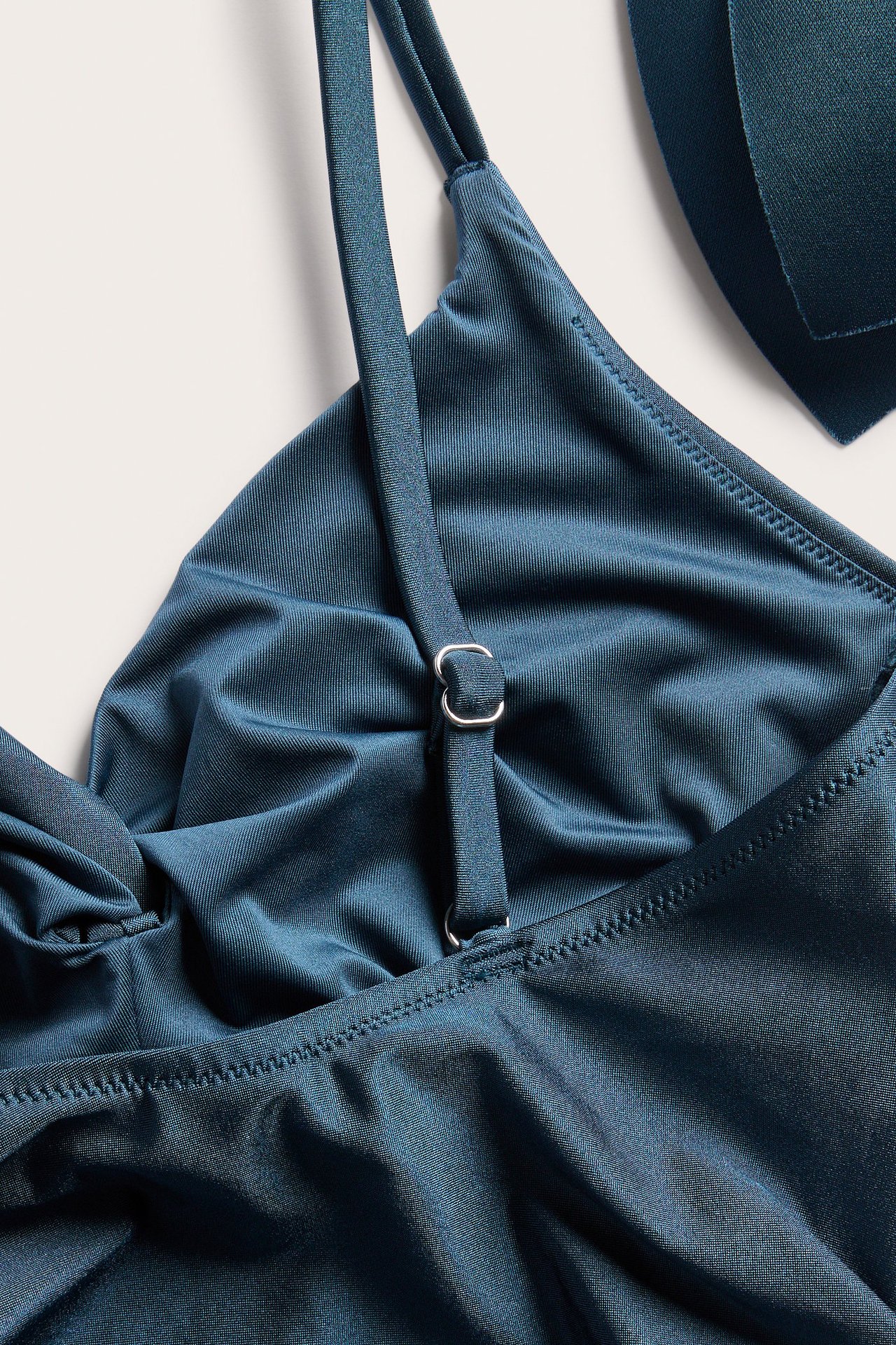 Zbliżenie ciemnoniebieskiego kostiumu kąpielowego ze skręceniem z przodu i regulowanym ramiączkiem.