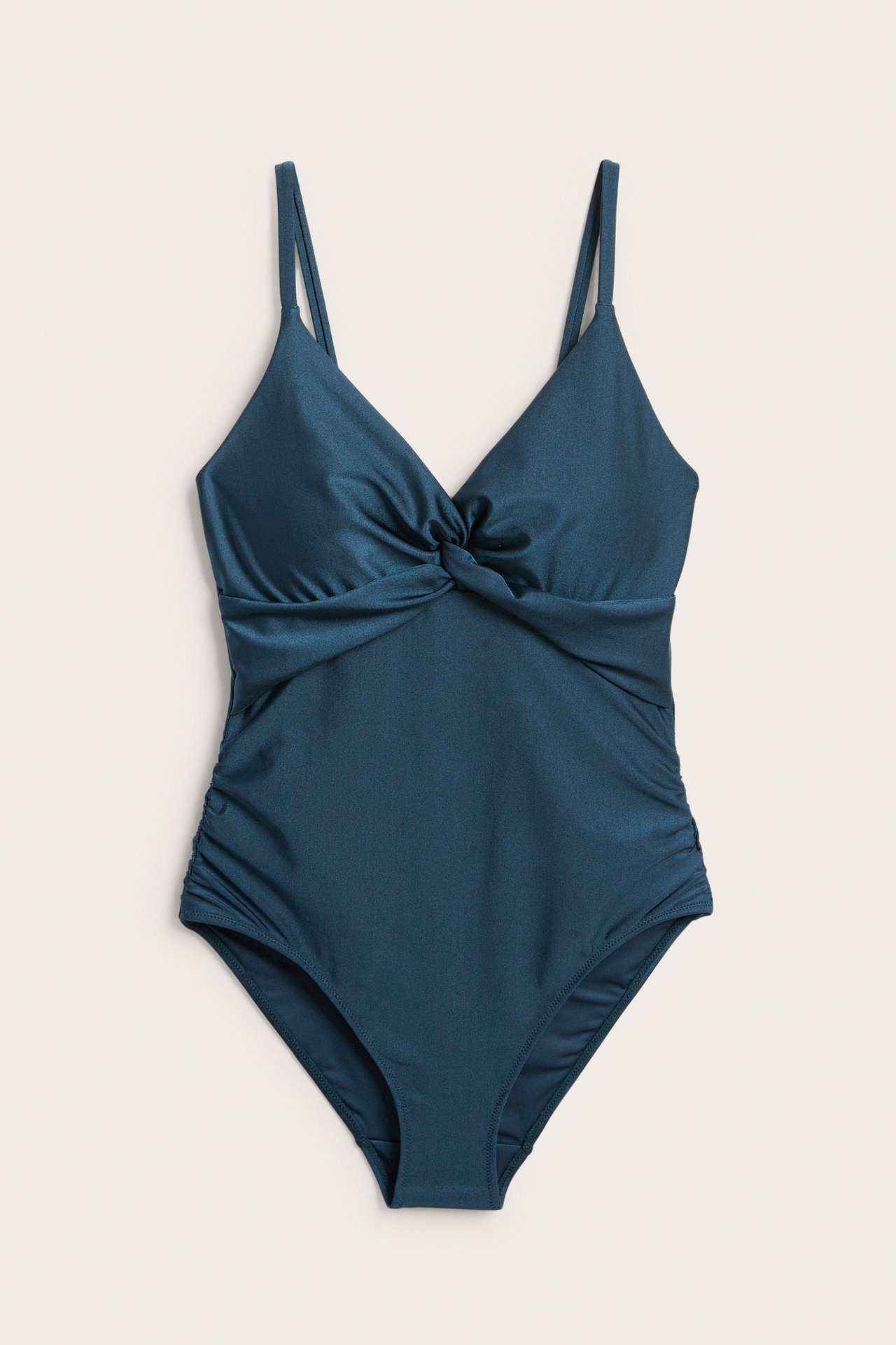 Z przodu: Granatowy kostium kąpielowy z marszczonymi bokami i skręconym przodem. Lekkie modelowanie.