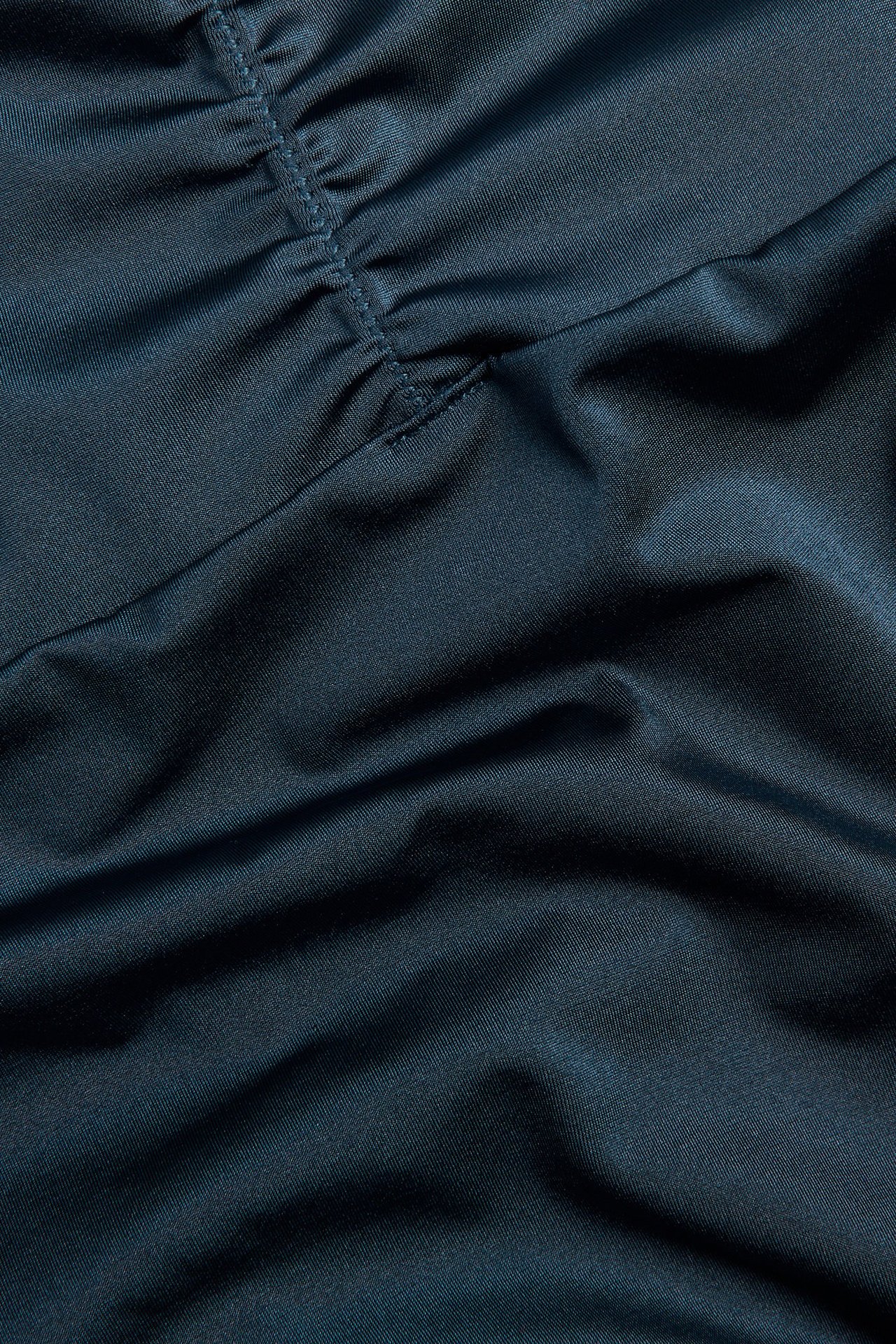 Zbliżenie na ciemnoniebieskie majtki bikini z drapowanym materiałem i jednolitym wzorem.