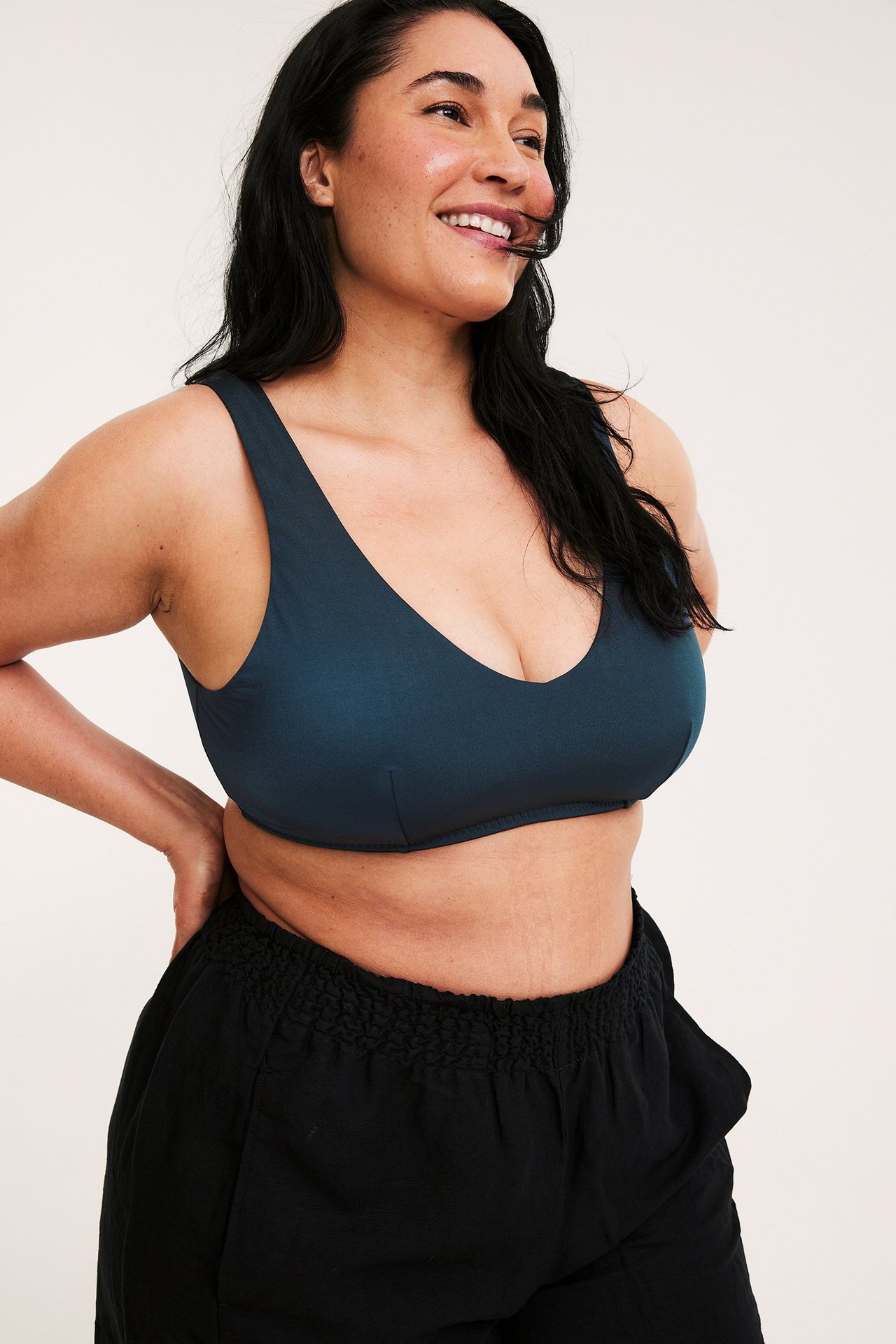 Framifrån-sida vy av en kvinna i en mörkblå vadderad bikinitopp och svarta shorts.