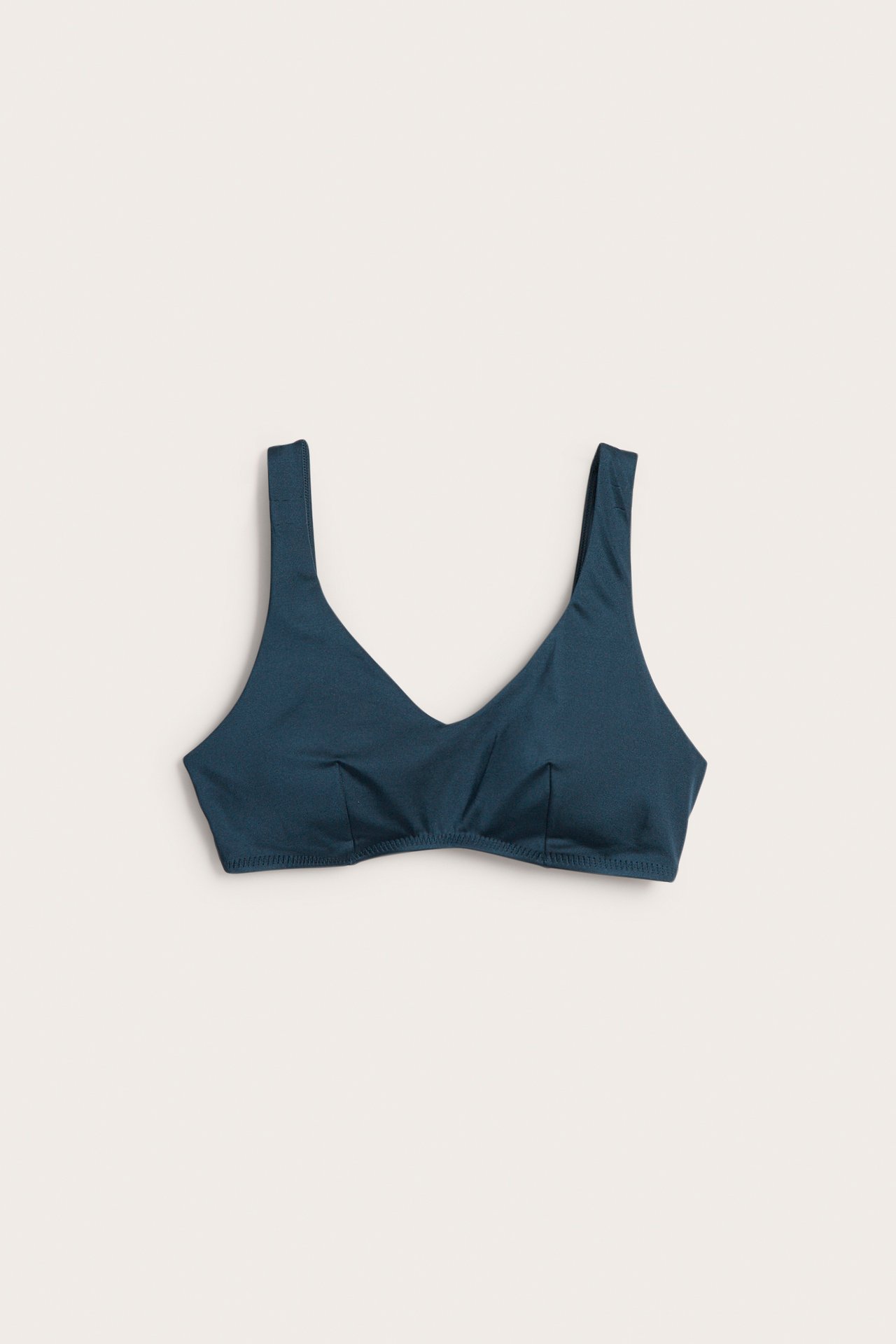 Frontvy av en mörkblå vadderad, bygelfri bikinitopp med breda axelband och V-ringning.