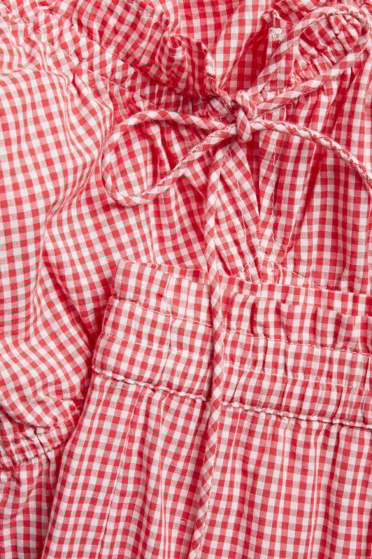 Närbild: Rött rutigt pyjamasset i bomull med rynkad topp, knytband fram och resårshorts.