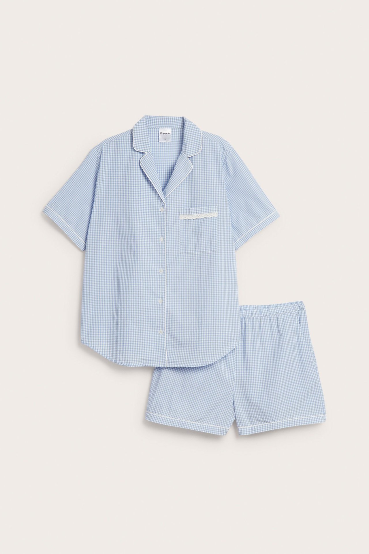 Framifrån: blåvitrutigt pyjamasset i bomull, vit passpoal, spetskantad bröstficka på skjorta, shorts.
