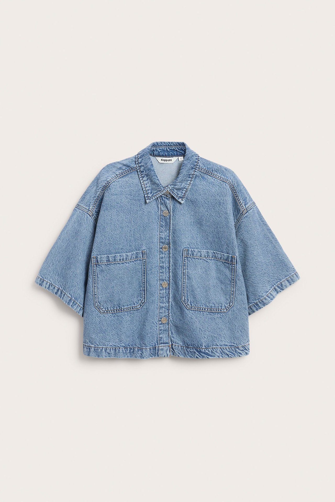 Edestä, vaaleansininen lyhyt denim-paita, lyhyet hihat, boxy-istuvuus ja napit edessä.