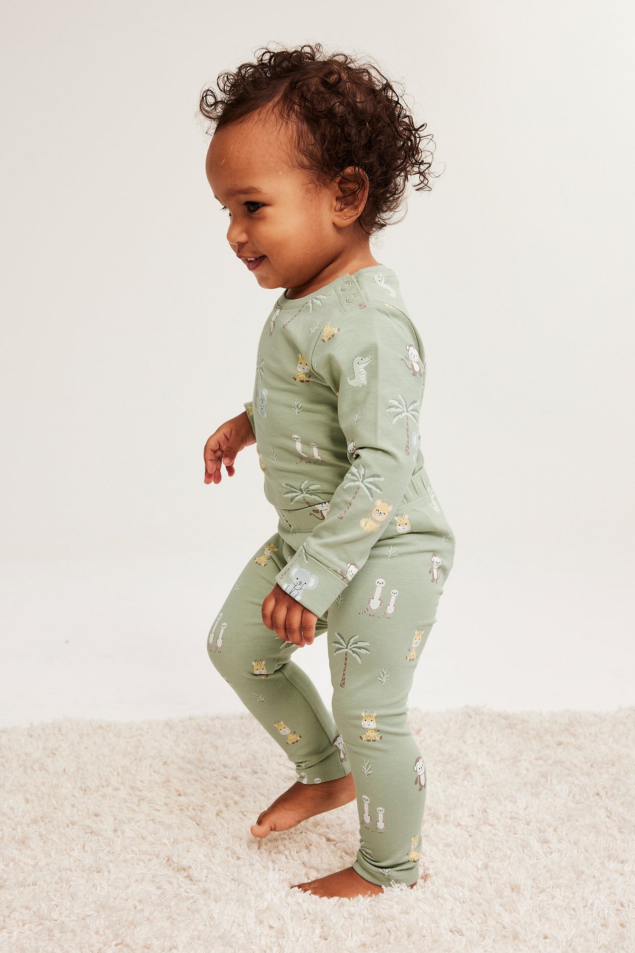 Vauvan sivukuva vaaleanvihreässä kuviollisessa puuvillasarjassa, jossa on eläinaiheita.