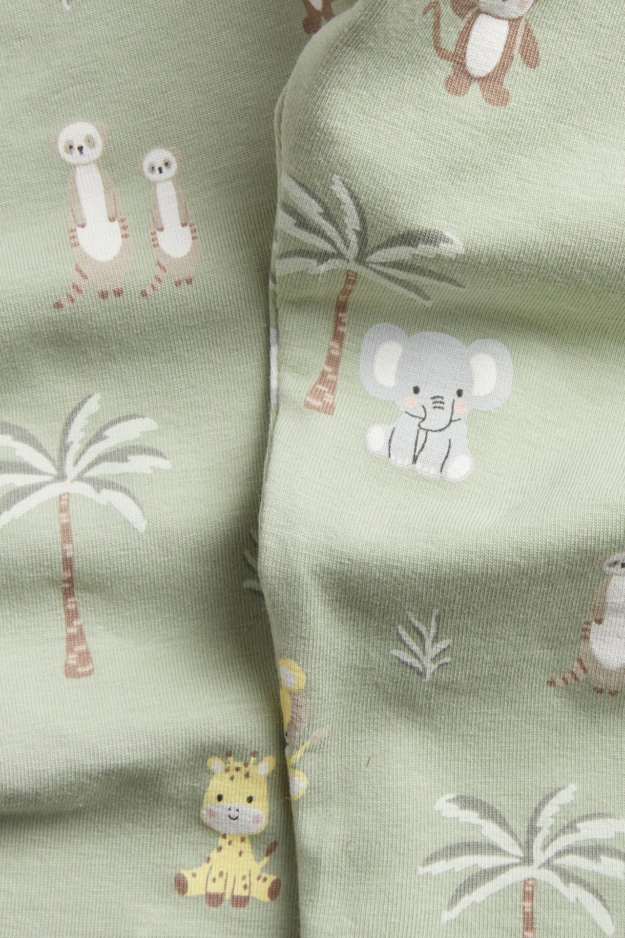 Zbliżenie zielonych, wzorzystych legginsów niemowlęcych z uroczymi motywami zwierząt i palm.