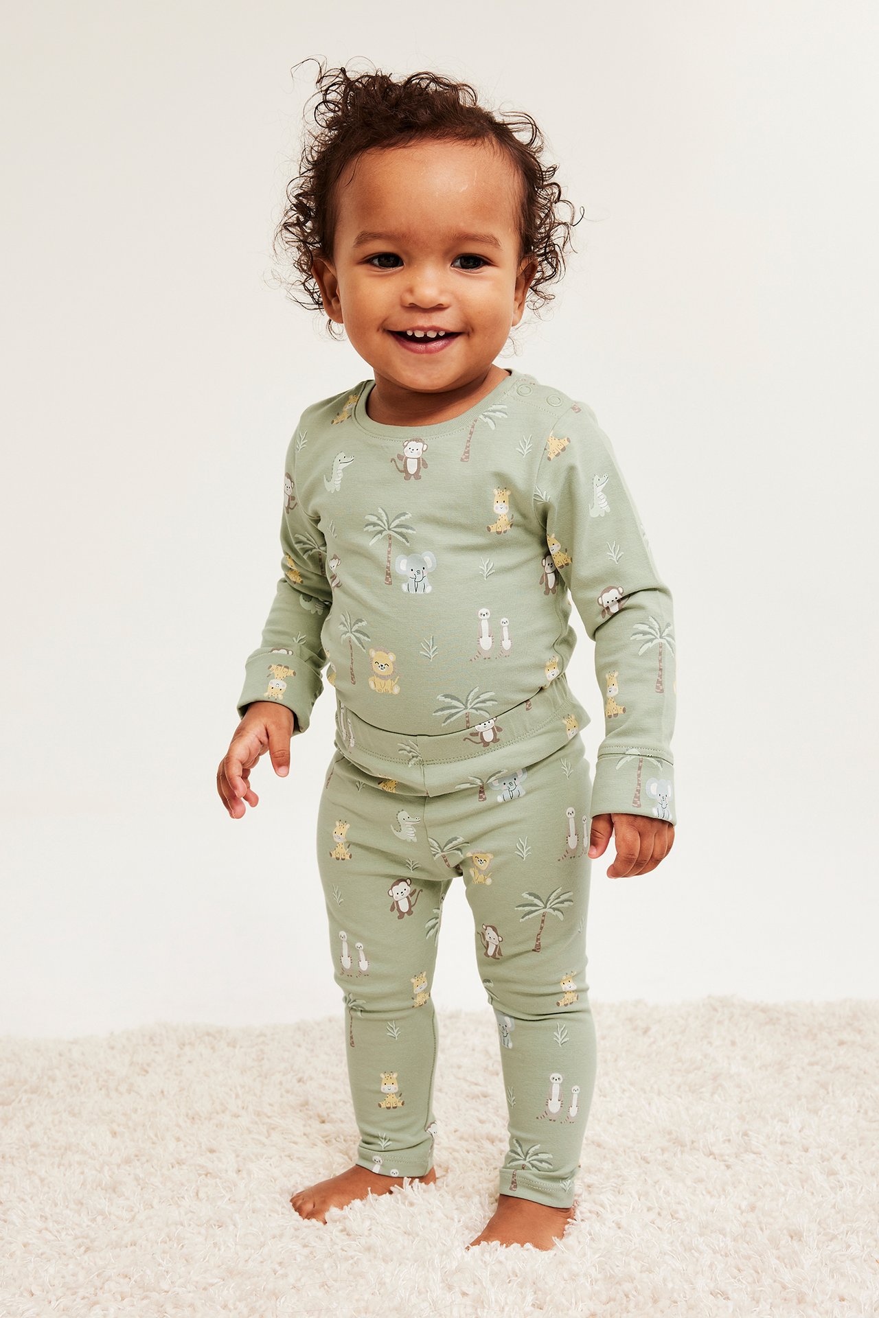 Edestä, vauva yllään vaaleanvihreä kuviollinen pitkähihainen paita ja yhteensopivat leggingsit eläinaiheella.