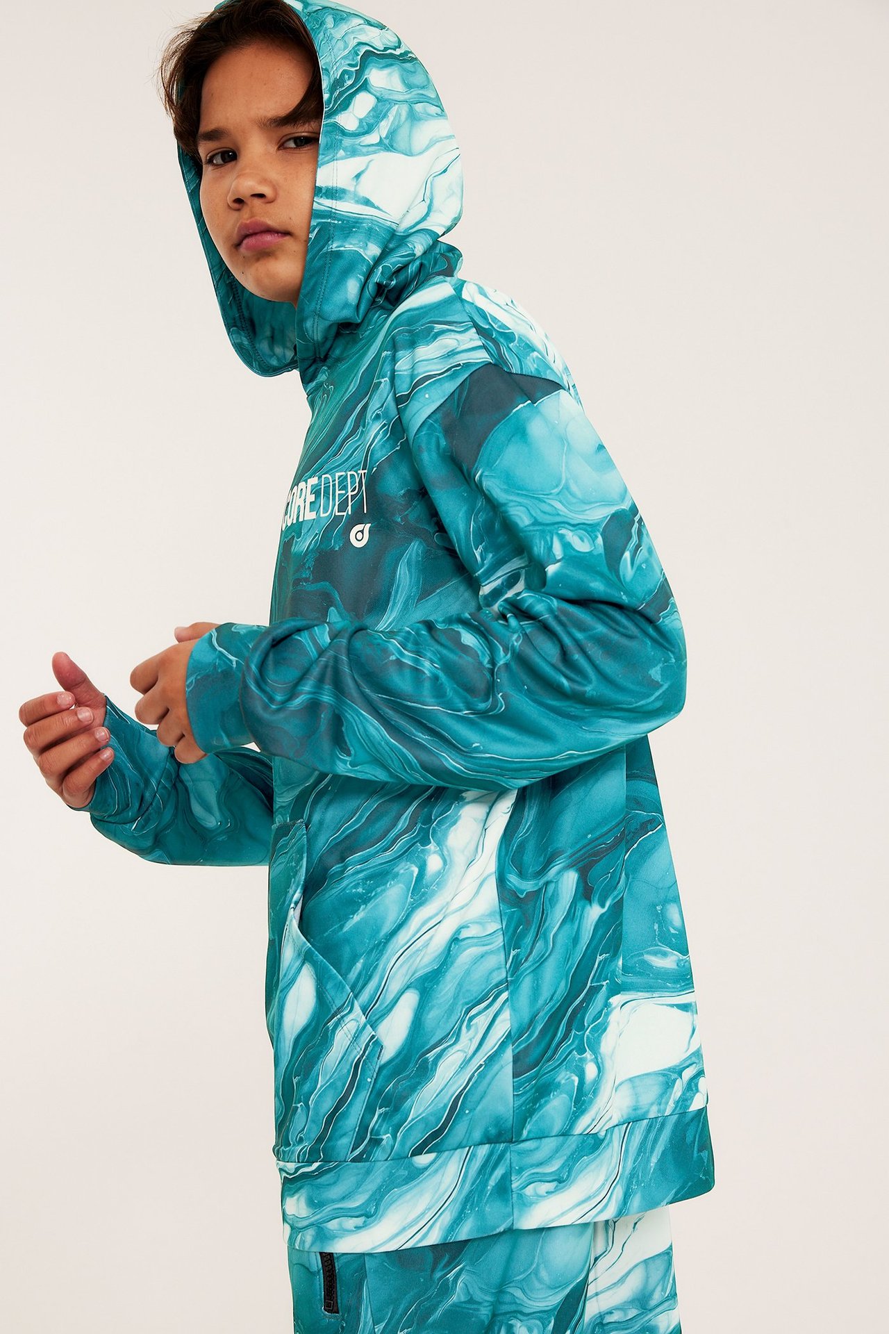 Widok z boku i przodu dziecka w zielonej bluzie WCT z marmurkowym wzorem i pasującymi spodniami.