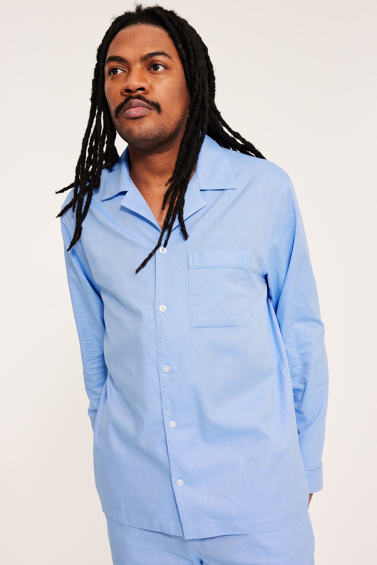 Framsida: Man bär ljusblått enfärgat pyjamasset i Oxford-bomull med knäppt överdel.