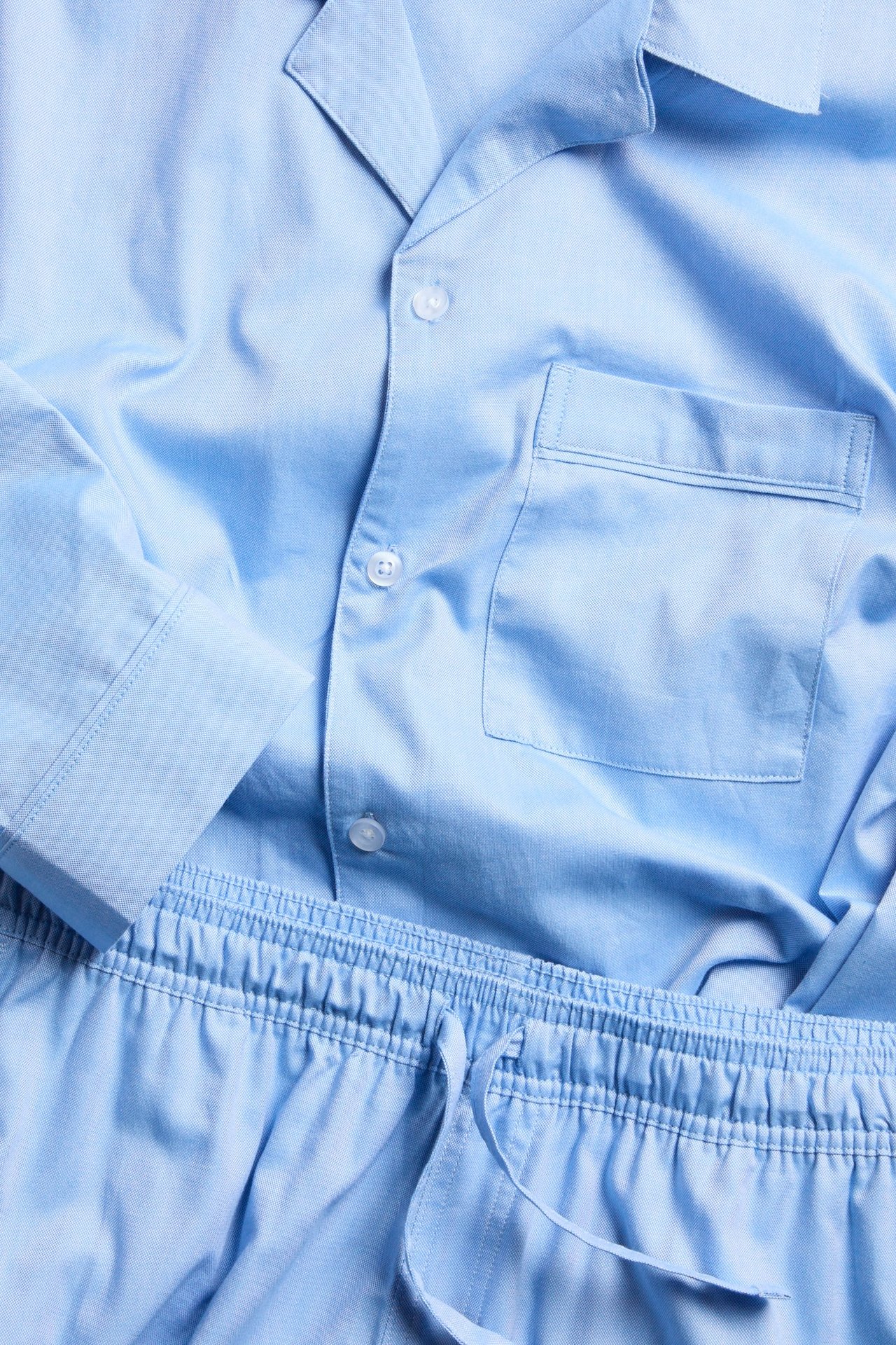 Zbliżenie: Jasnoniebieska piżama męska z bawełny Oxford, zapinana góra z kieszenią, spodnie z gumką i sznurkiem.