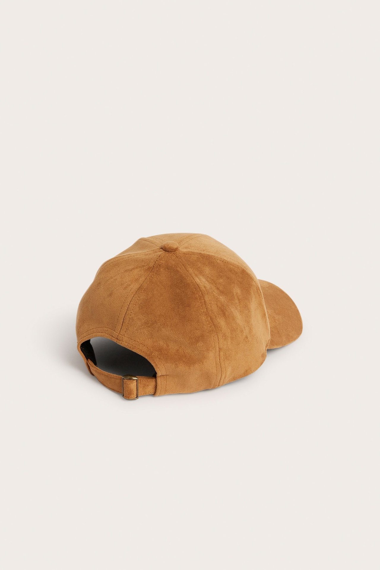 Bakfra, lys brun ensfarget caps i fusk semsket skinn med metallspenne bak.