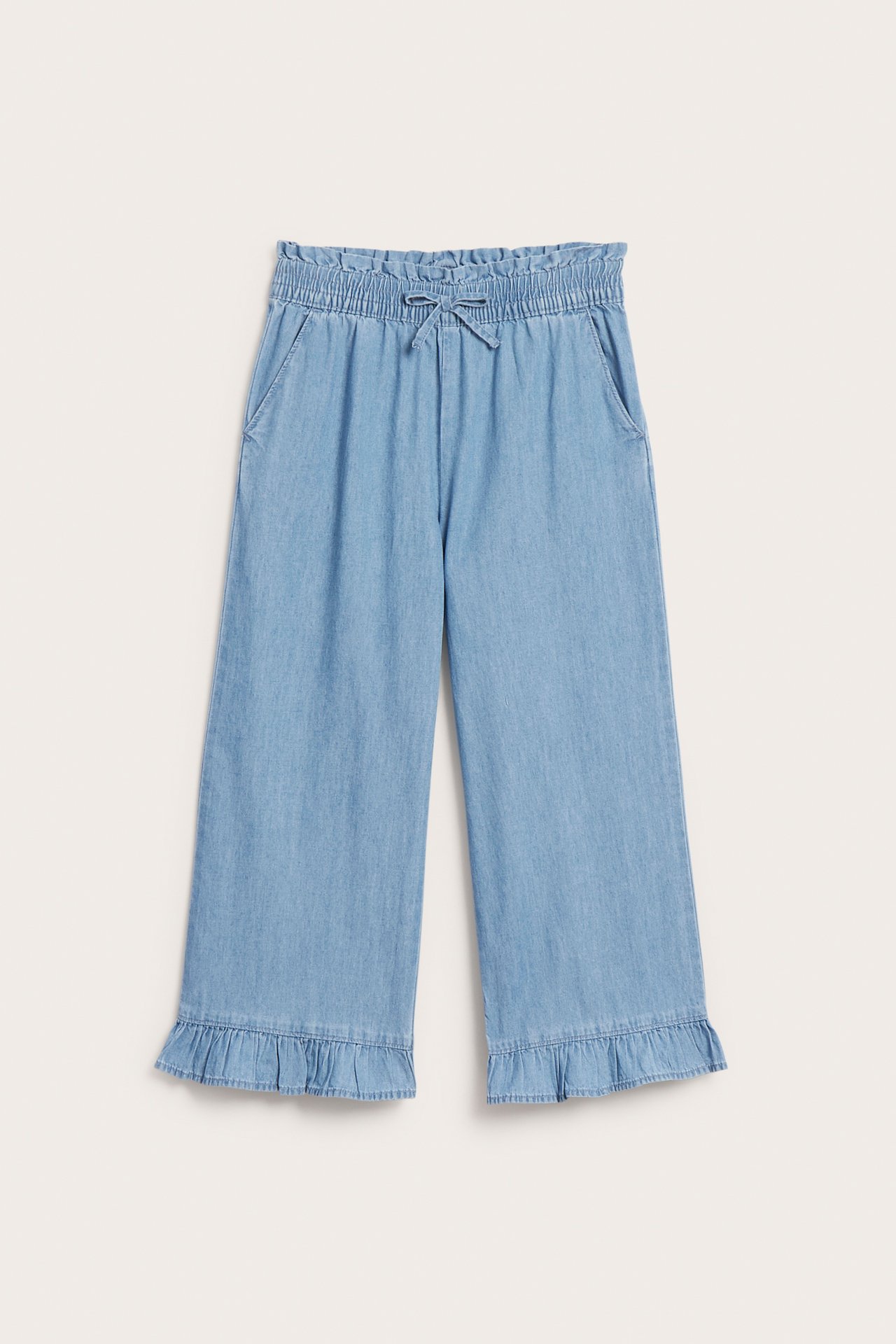 Widok z przodu: jasnoniebieskie, szerokie dżinsowe spodnie z marszczoną elastyczną talią, kokardą ze sznurka i falbankami.