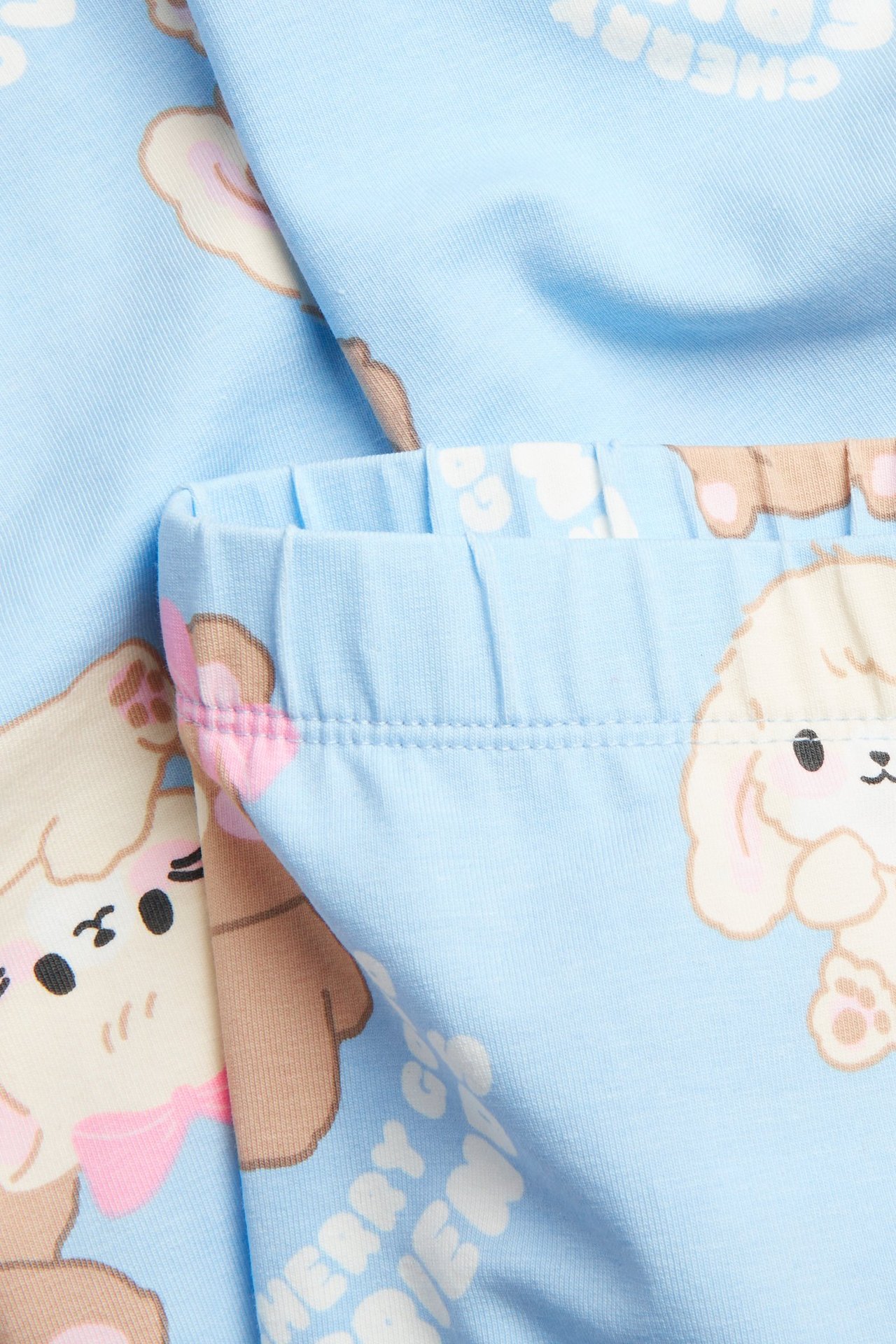 Zbliżenie na jasnoniebieskie legginsy z dżerseju, z elastycznym pasem i nadrukiem zwierząt kawaii.