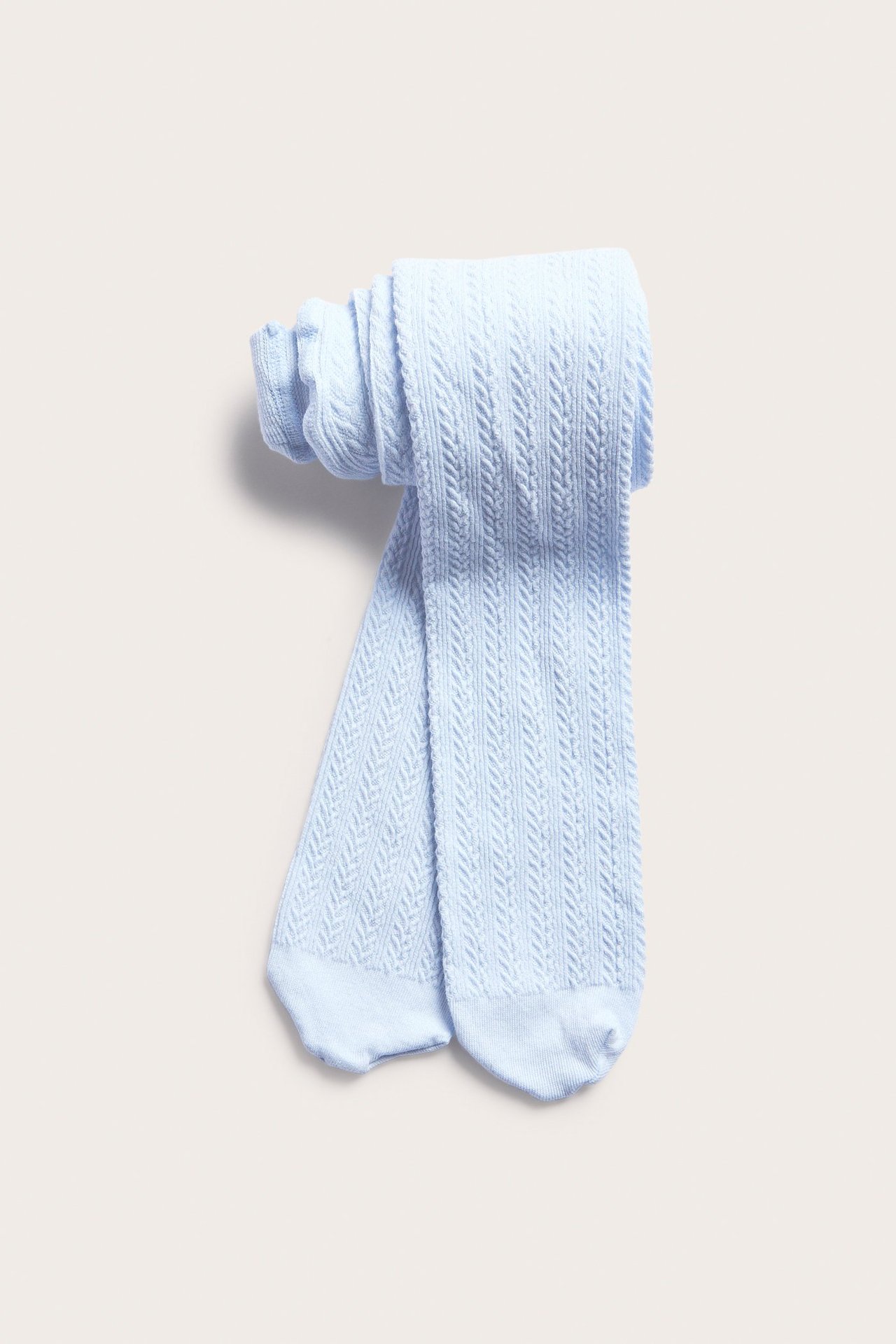Widok z góry na złożone jasnoniebieskie rajstopy z bawełny o warkoczowym splocie.