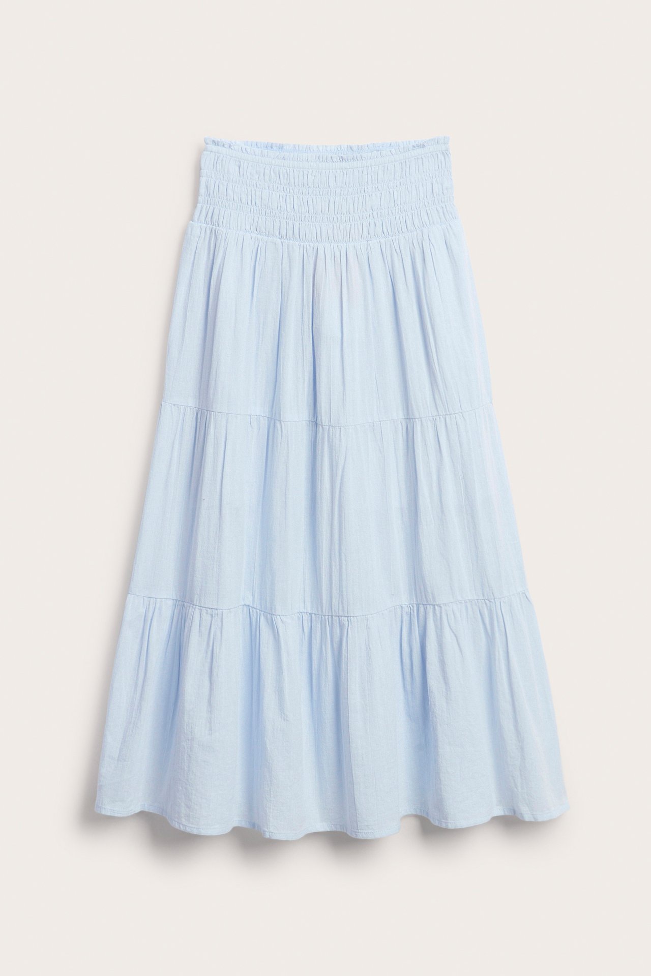 Edestä, lasten vaaleansininen puuvillainen maksihame, jossa on smokkirypytetty vyötärö ja kerrokselliset röyhelöt.