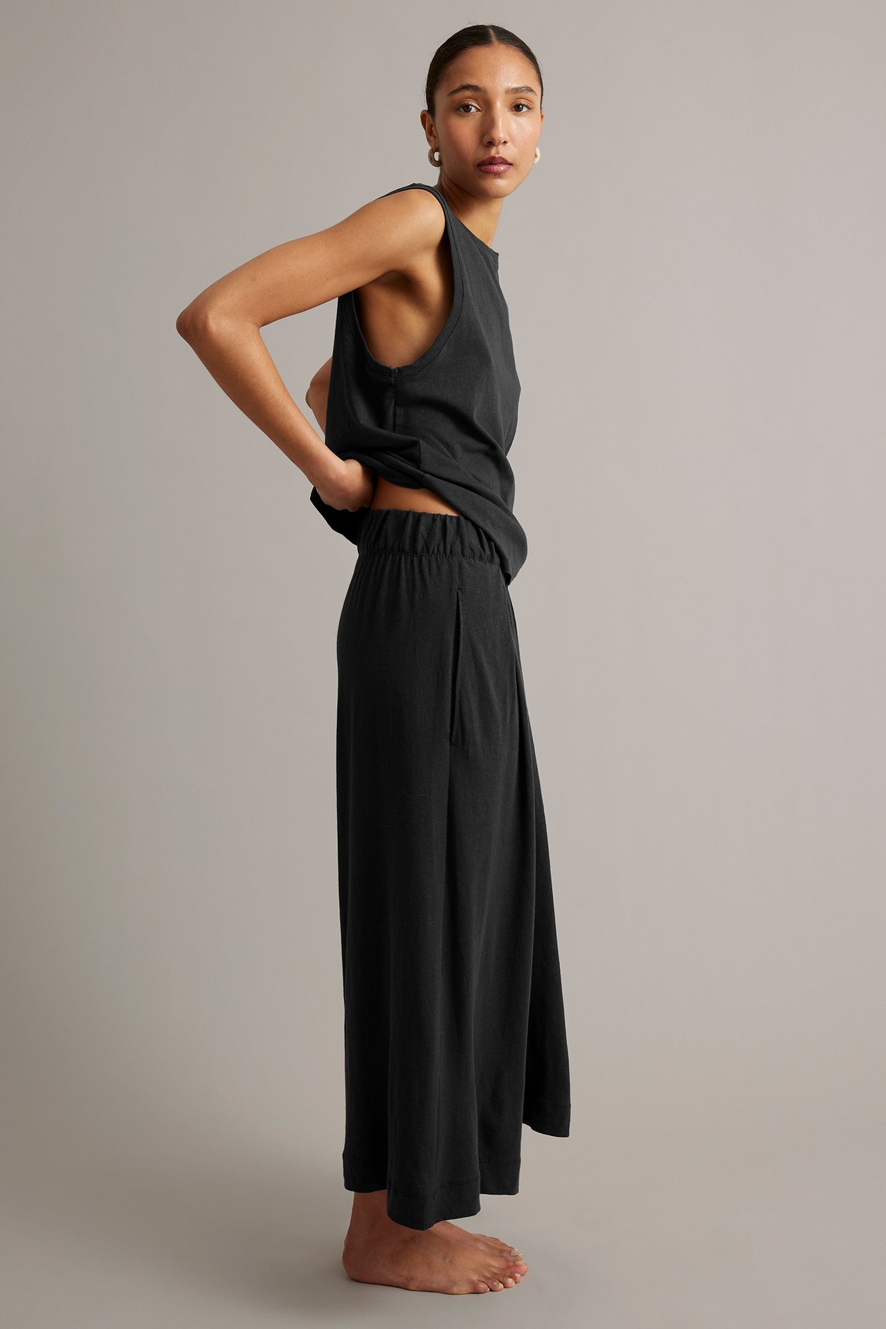 Sidovy: Kvinna i svarta culottebyxor i linneblandning med fickor och matchande ärmlös topp.