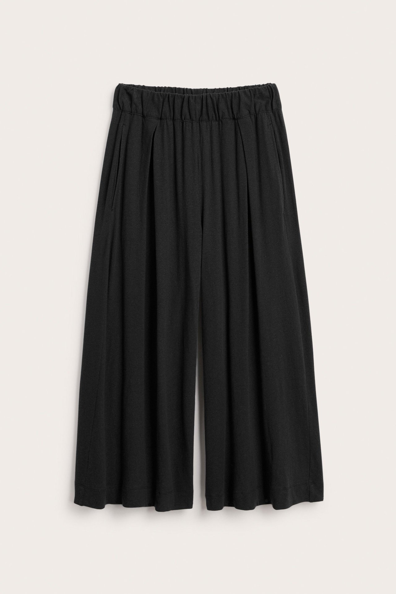 Frontvy av svarta culottebyxor i bomull-linne med veck fram, sidfickor och resår i midjan.