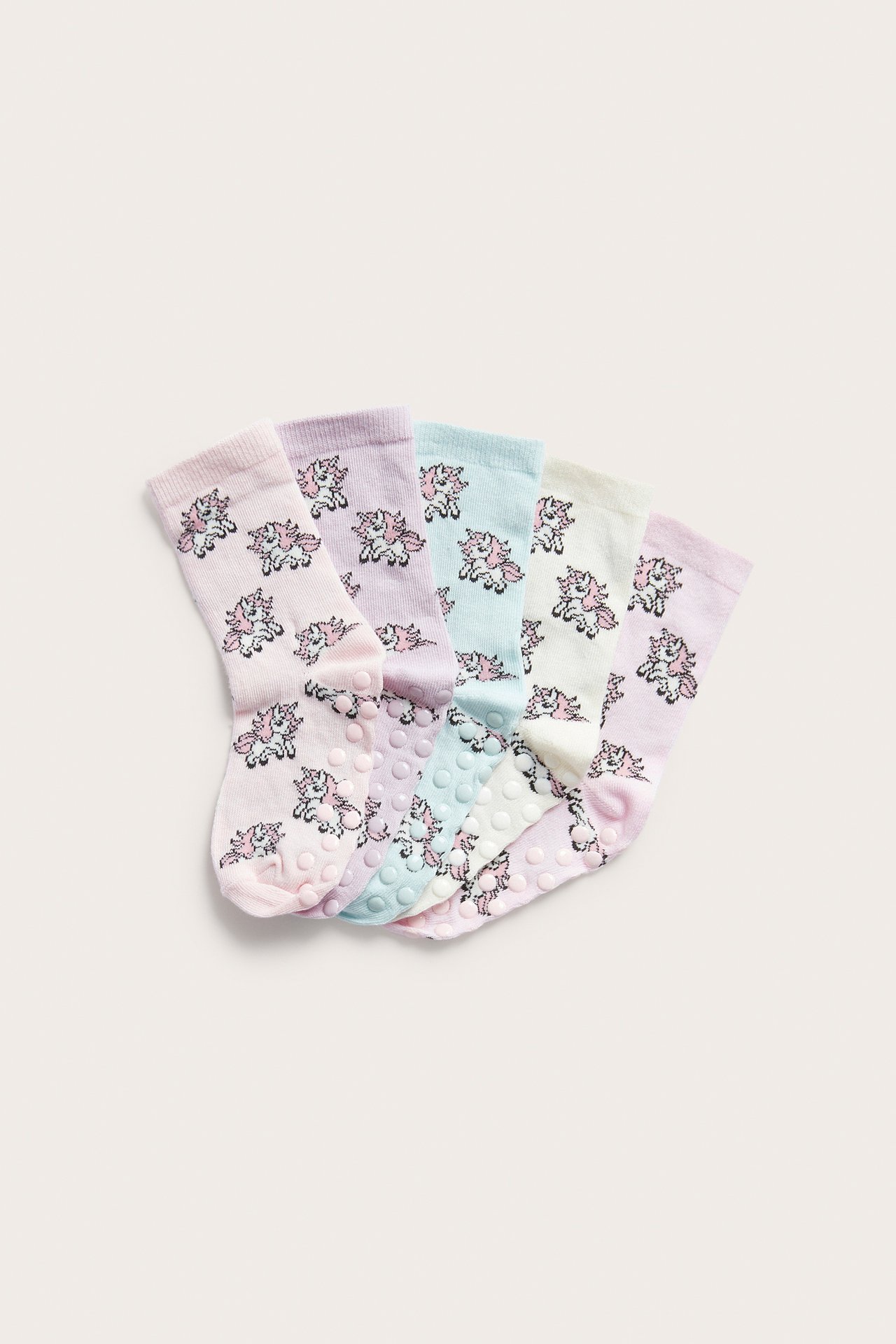 Fem par barnstrumpor med enhörningsmönster i pastellfärger, med antislip-sulor.