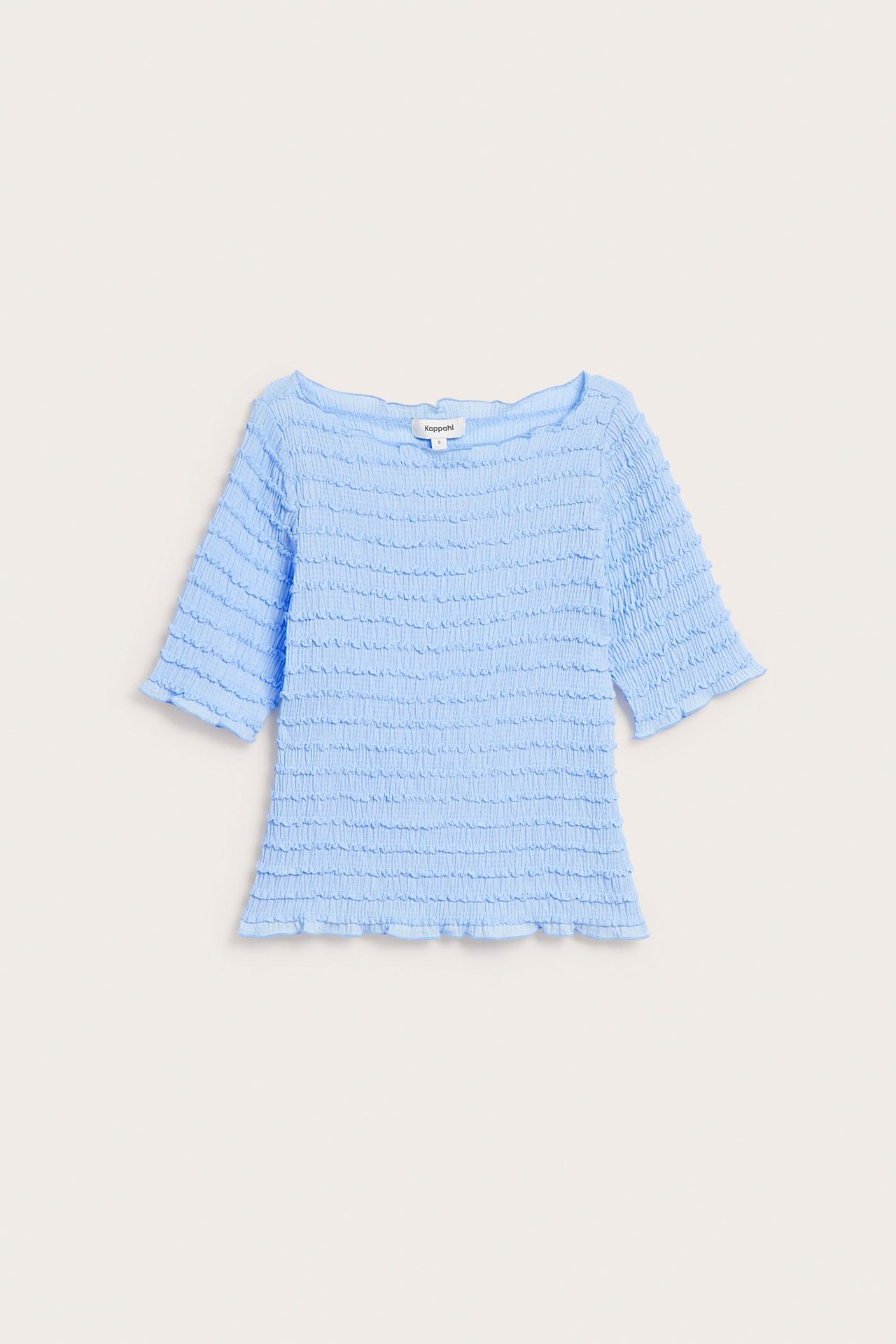 Edestäpäin vaaleansininen kuvioitu toppi, jossa on venekaulus ja kolmevarttiset hihat.