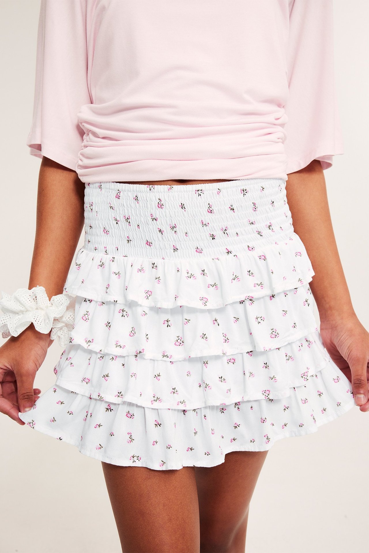 Widok z przodu: Dziecko w białej wiskozowej spódnicy z różowym wzorem kwiatowym, różowym topie i białej gumce.