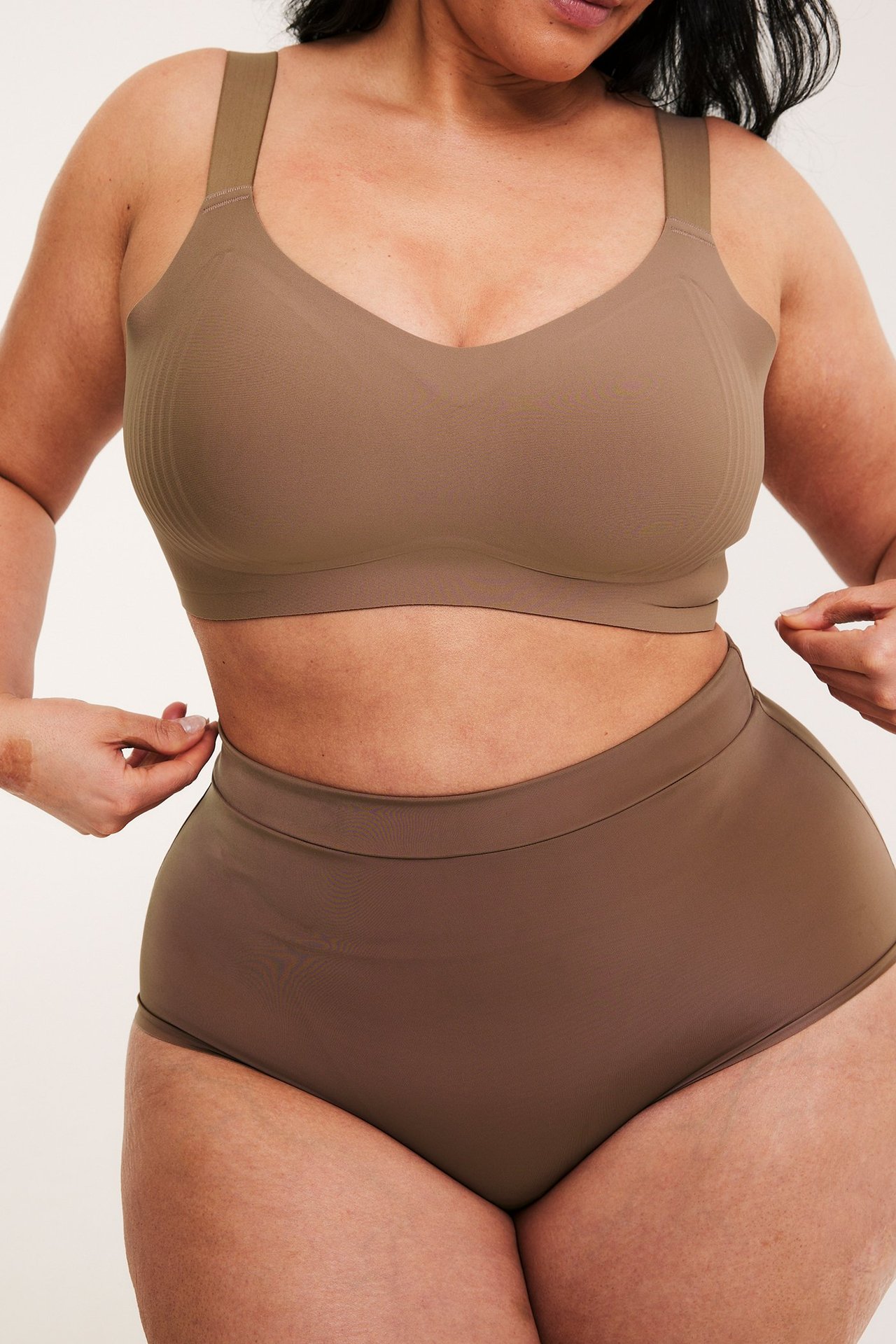 Edestäpäin, nainen yllään ruskeat saumattomat korkeavyötäröiset hipsterit ja yhteensopivat rintaliivit.