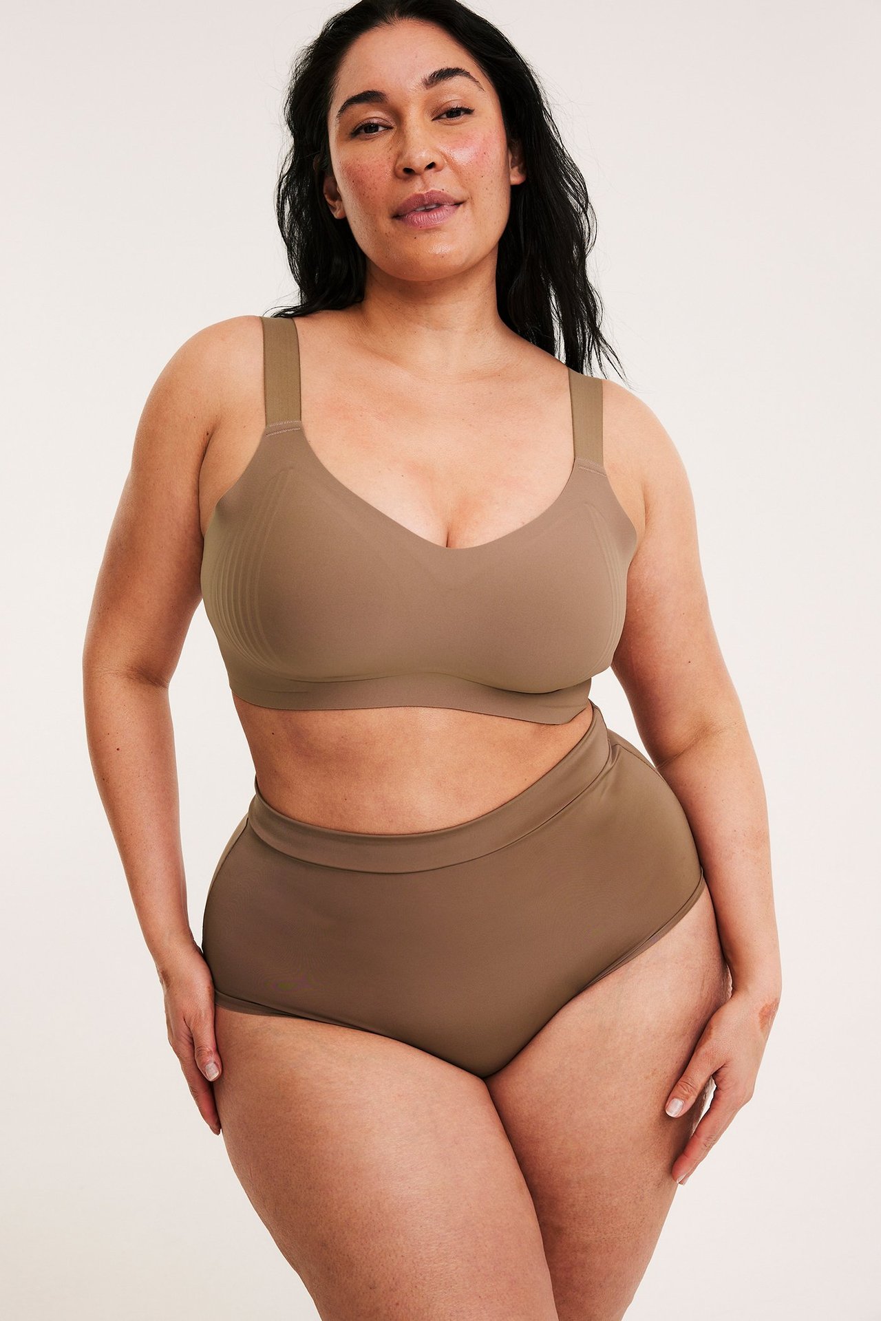 Forfra, kvinne i brun sømløs mikro hipstertruse med elastisk linning og matchende bralette.