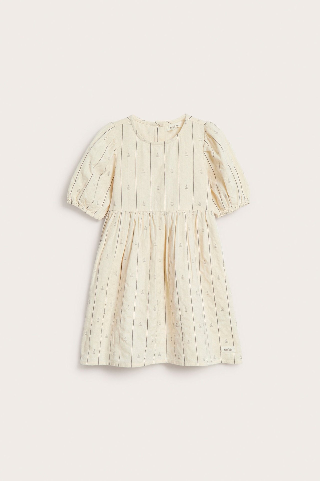 Framsida av en barnklänning i off-white med ränder, små segelbåtar, puffärm och knappar i ryggen.