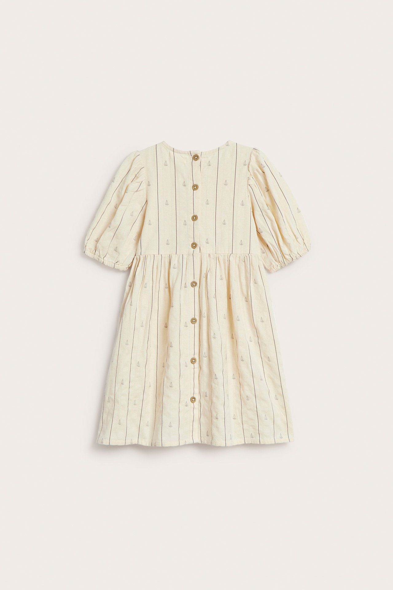 Bakifrån av en vit kortärmad bomullsklänning för barn med ränder, segelbåtar, puffärmar och ryggknappar.