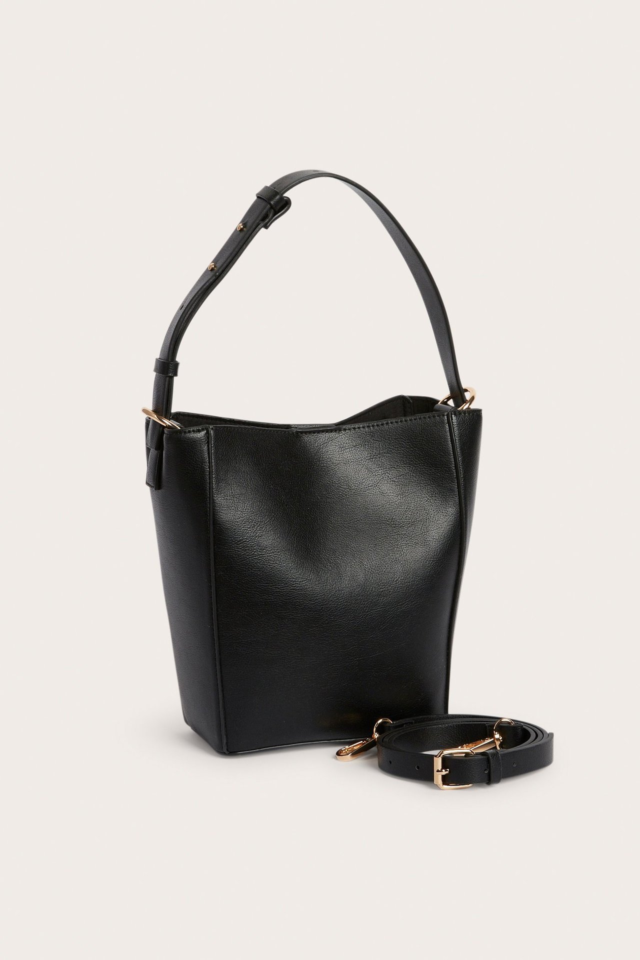 Edestä: Musta bucket-laukku lyhyellä kantokahvalla. Erillinen säädettävä pitkä olkahihna sisältyy.