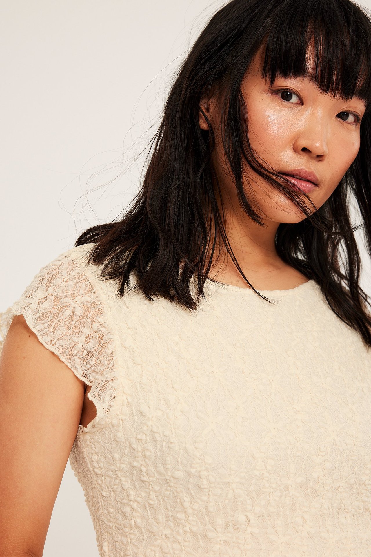 Vit kortärmad topp i spets och body i samma material, nära kropp, frontvy.