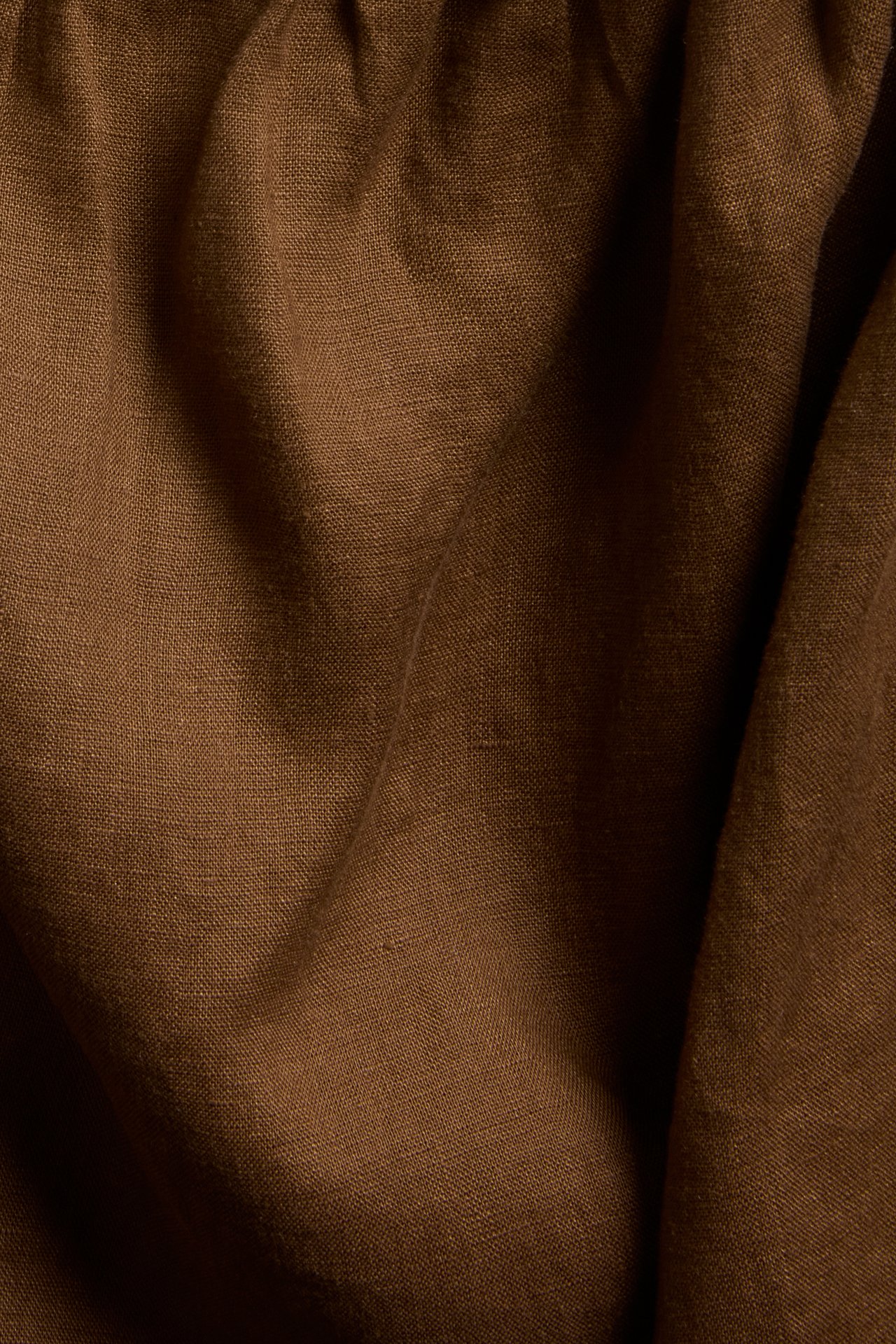 Närbild av brunt enfärgat linne, avsett för ett linne, med mjuka veck.