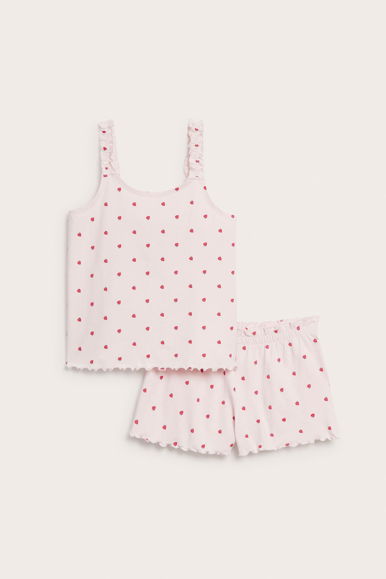 Forfra: Barns lyserosa bomullspysjamas med rødt jordbærmønster, volangkantede stropper og bølgete kanter.