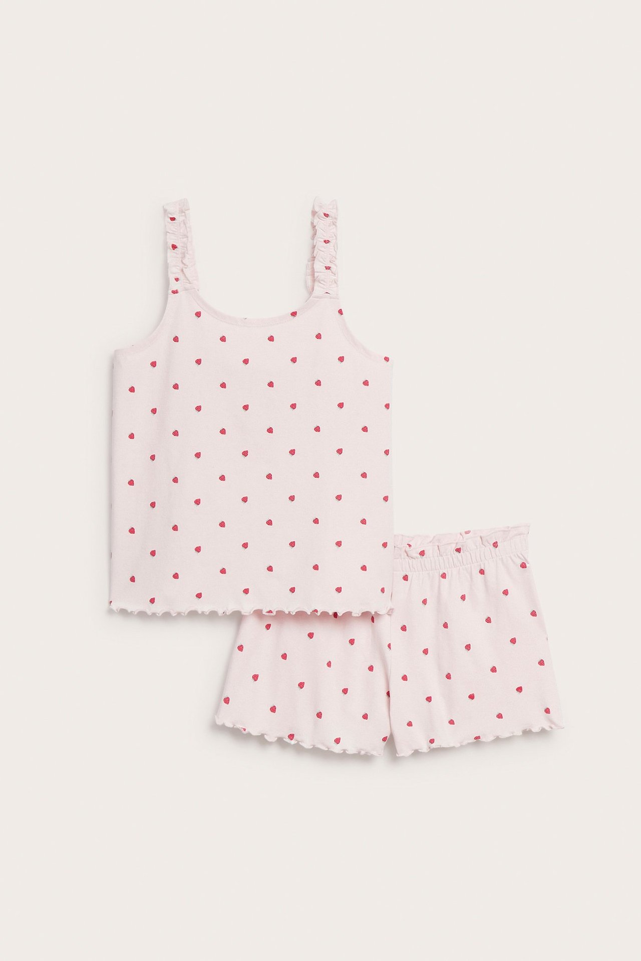 Edestä: Lasten vaaleanpunainen puuvillapyjamas mansikkakuviolla, röyhelöolkaimilla ja aaltoilevilla reunoilla.