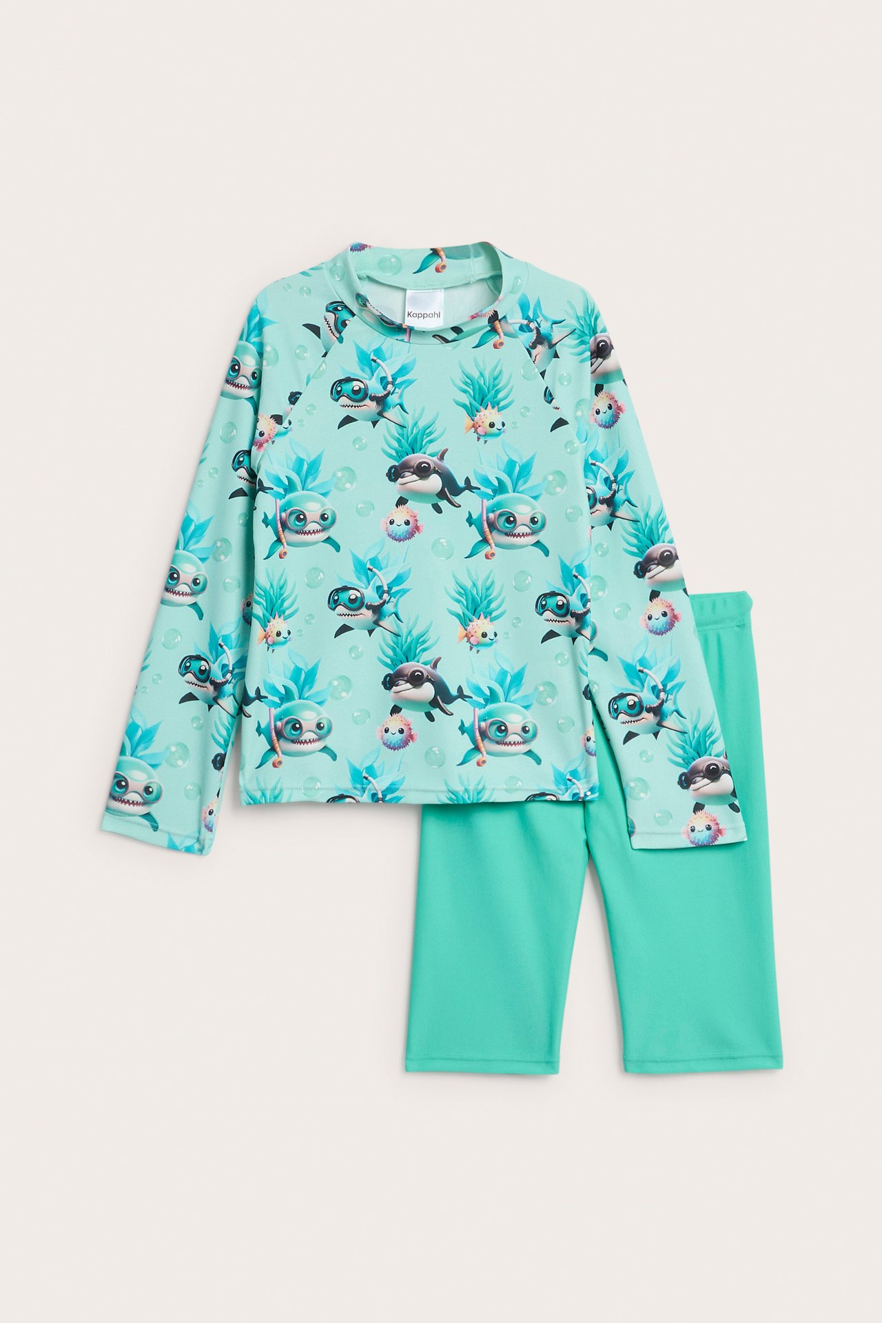 Forfra, et lys turkis UV-sett for barn: langermet topp med haimønster og ensfargede korte bukser.
