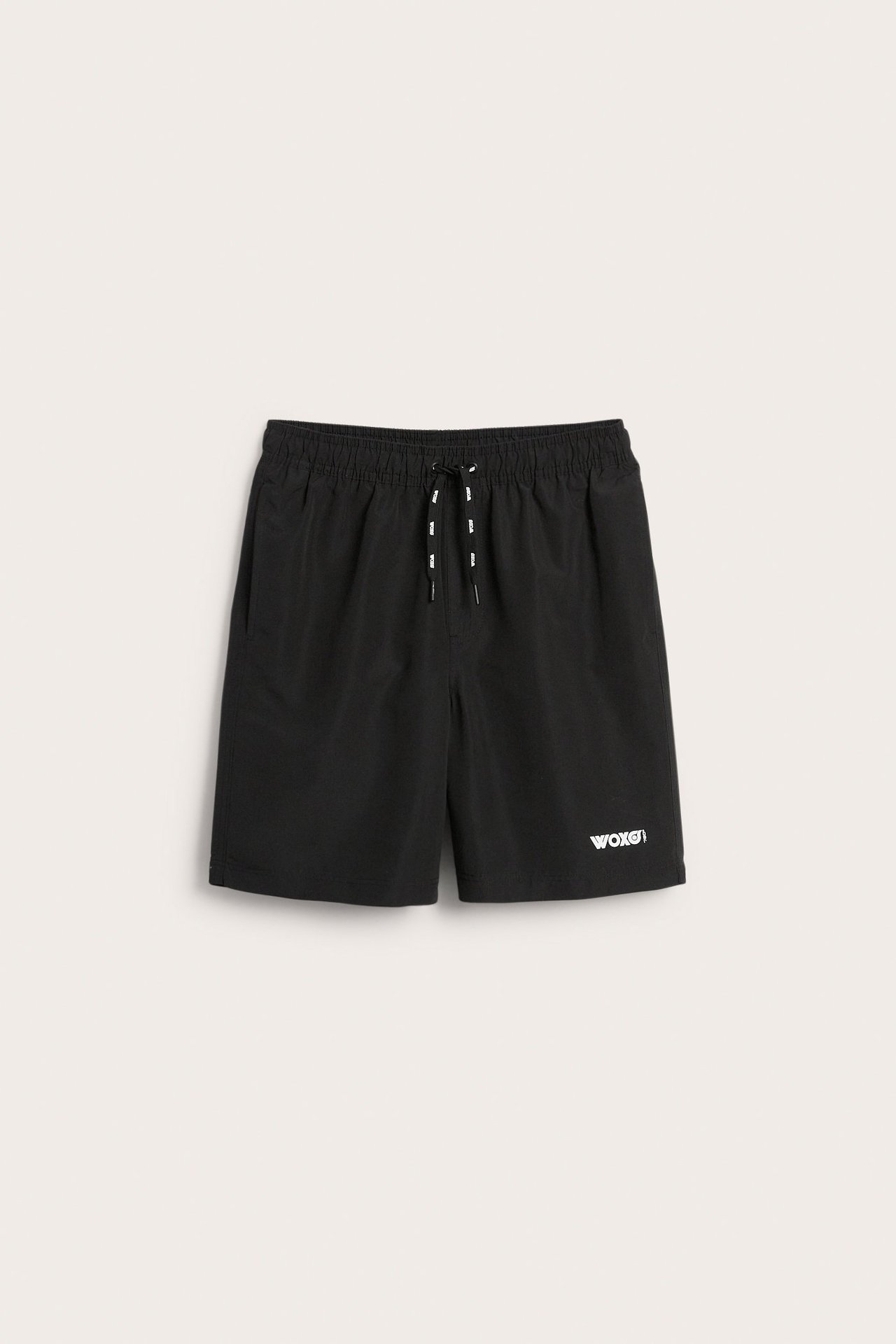 Edestäpäin, mustat uimashortsit, joissa joustava vyötärö, valkoinen kiristysnyöri ja valkoinen 'WOXG!'-logo.