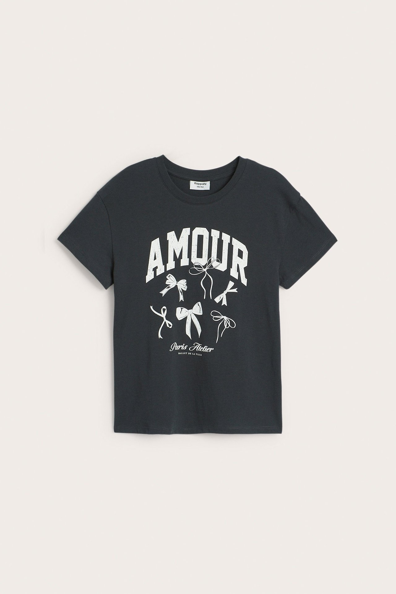 Framsida av en svart kortärmad T-shirt i bomull för barn med vitt 'AMOUR'-tryck och rosetter.
