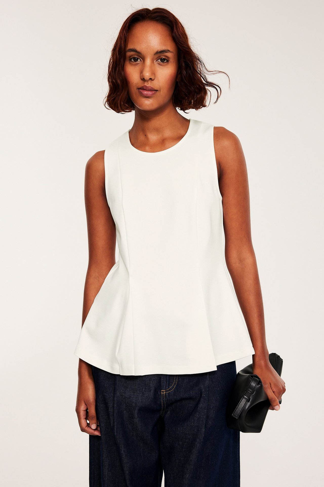 Offwhite peplum singlet i ponte med rund hals, ermløs, brukt av kvinne.